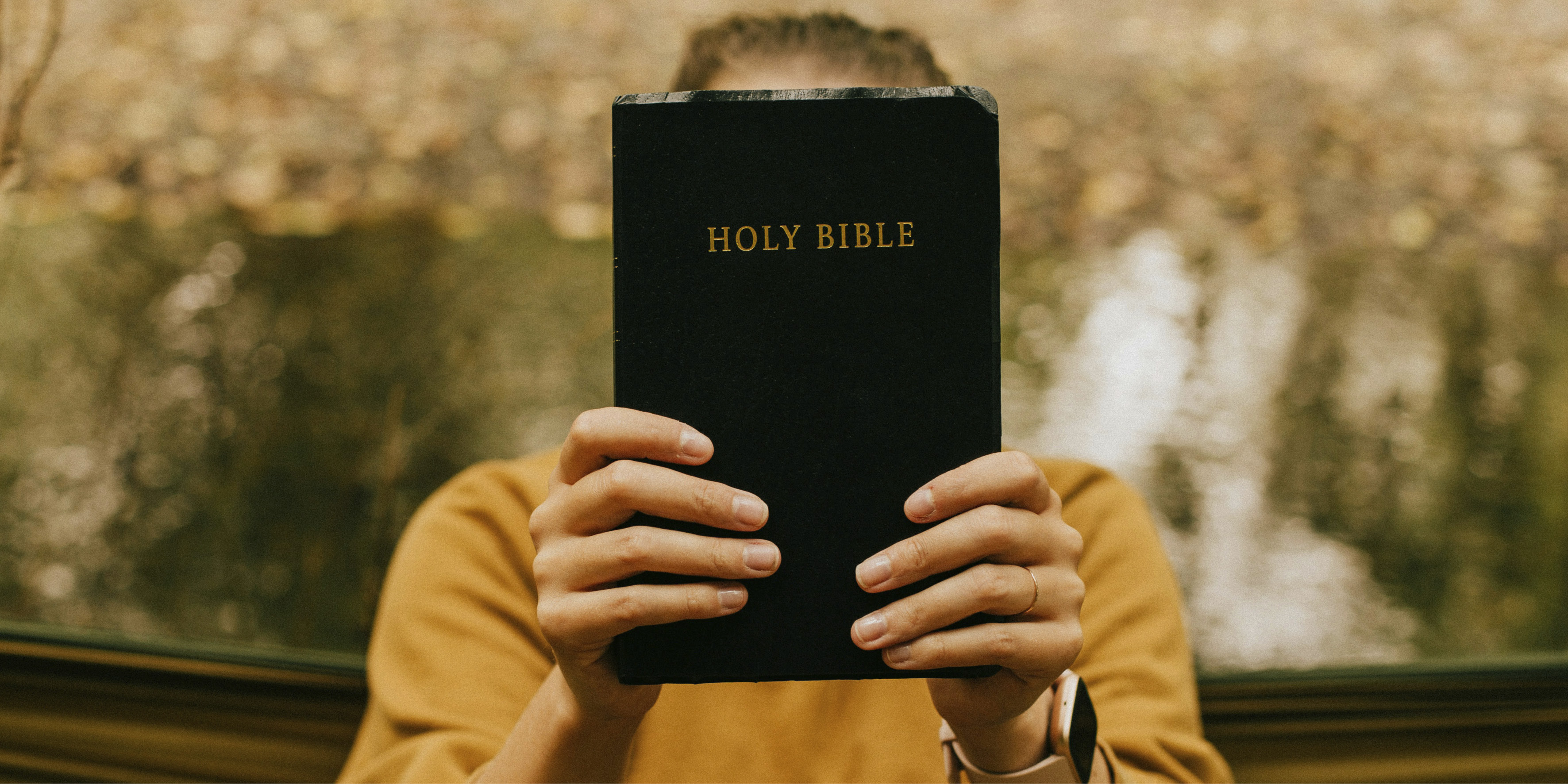 En kvinna håller upp en bibel framför ansiktet. 
