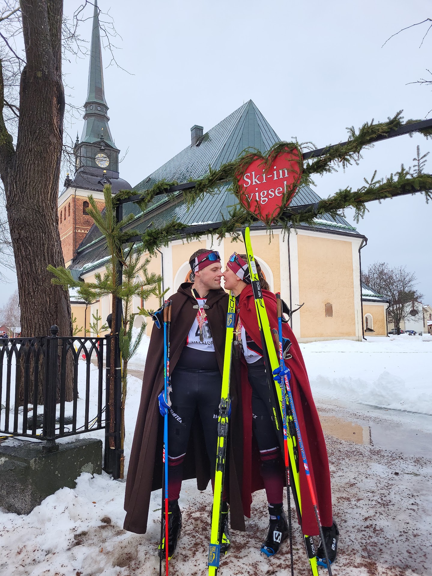 Nygift par ståendes med längdskidor vid målgången av Vasaloppet 2024.