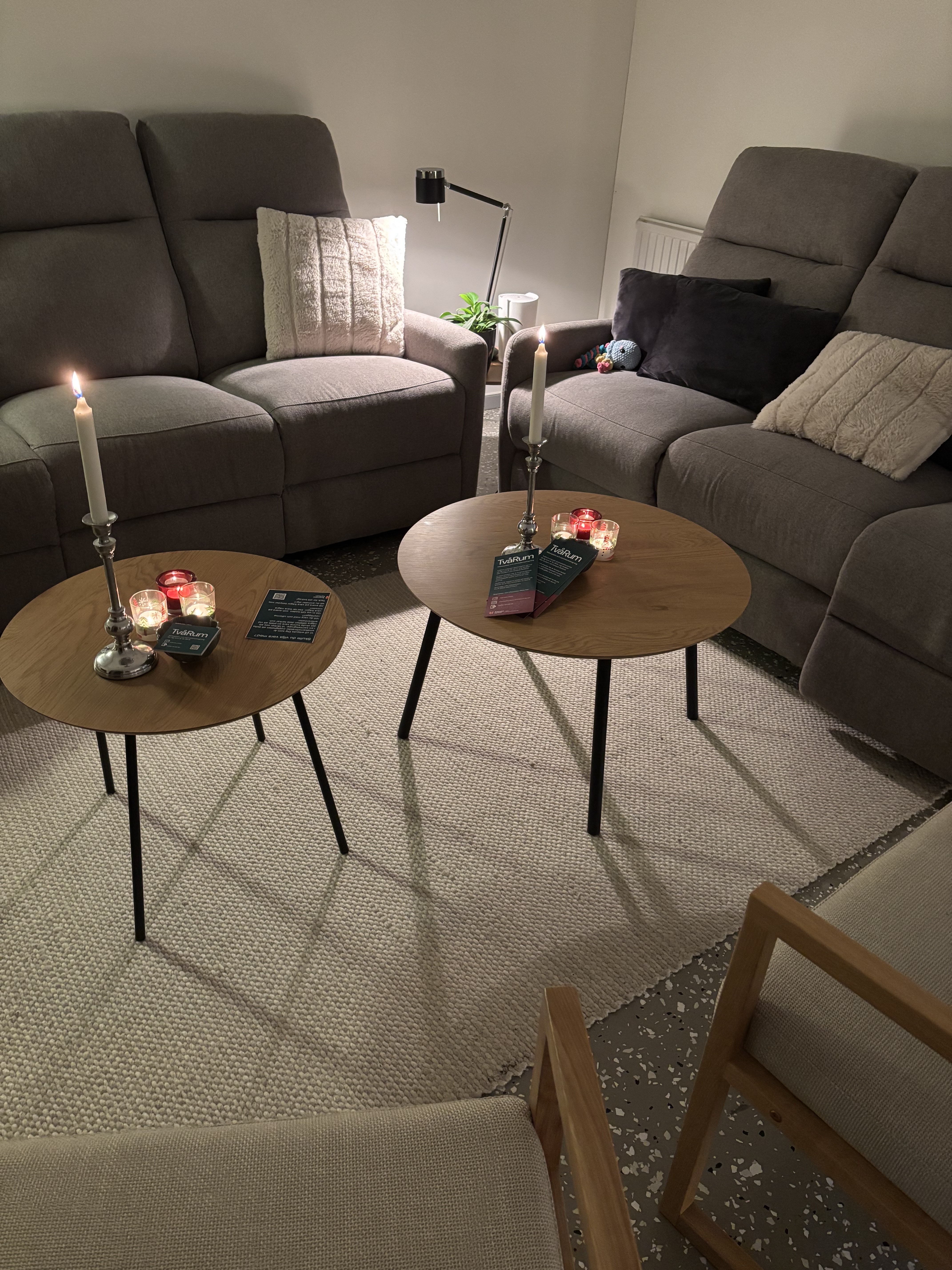 Ett rum med två bord med tända ljus och en soffa.