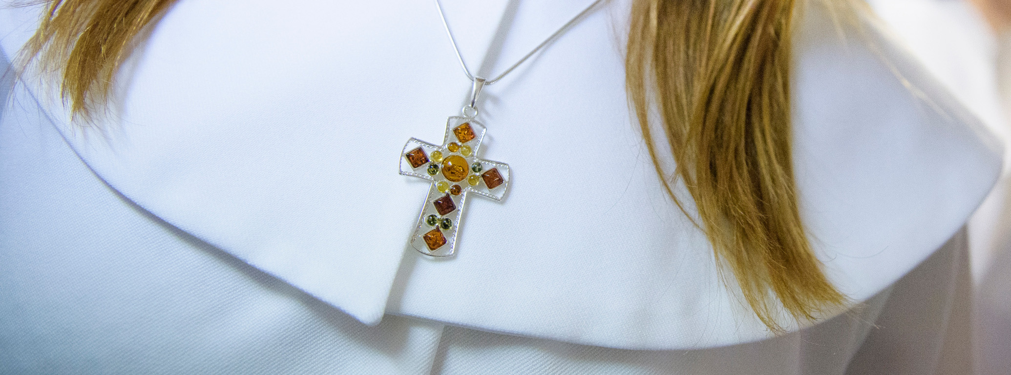 Inzoomning på konfirmandkåpans krage med ett kors på ett halsband i mitten.