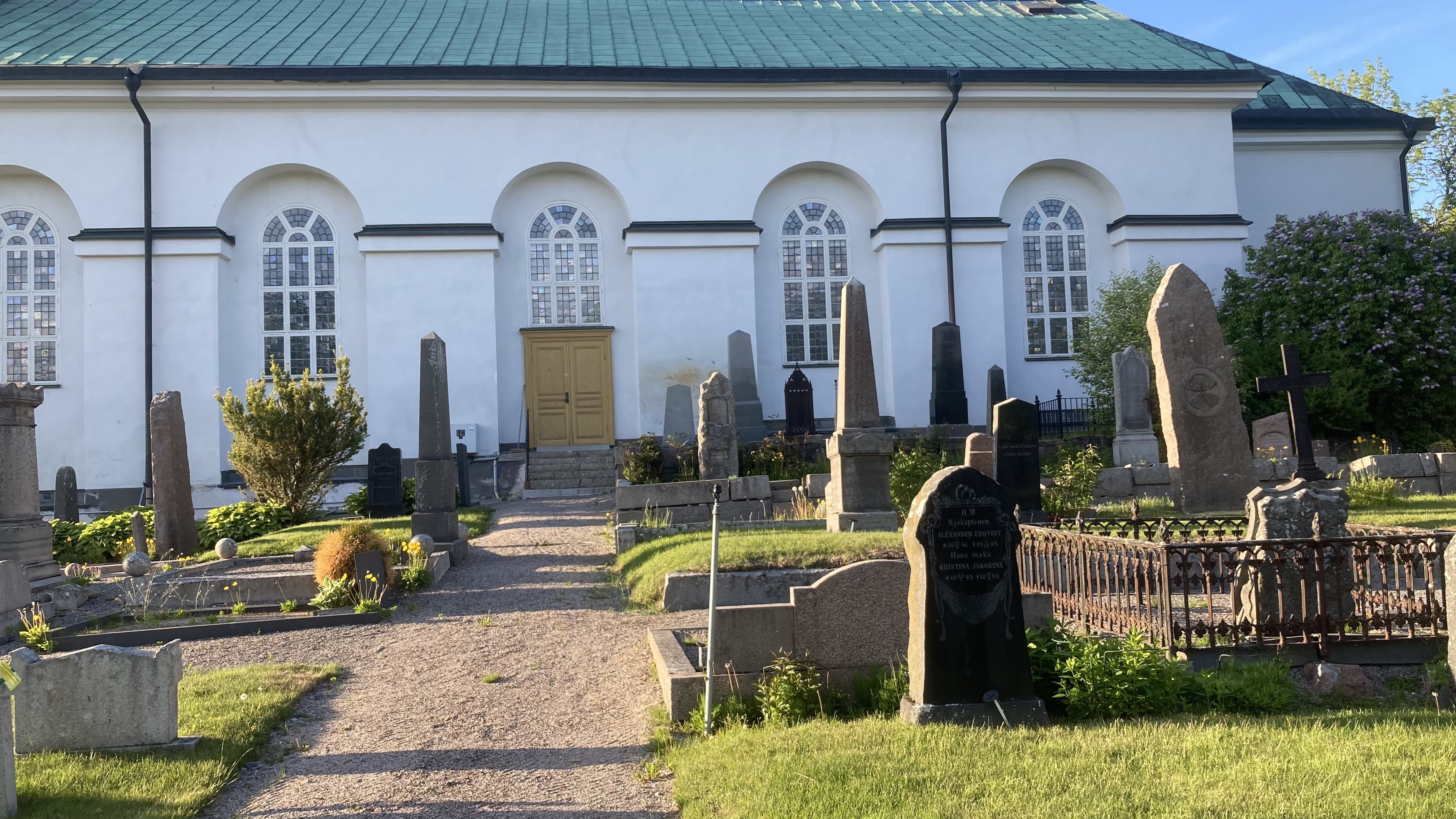 Kyrkogård med en vit kyrka i bakgrunden.