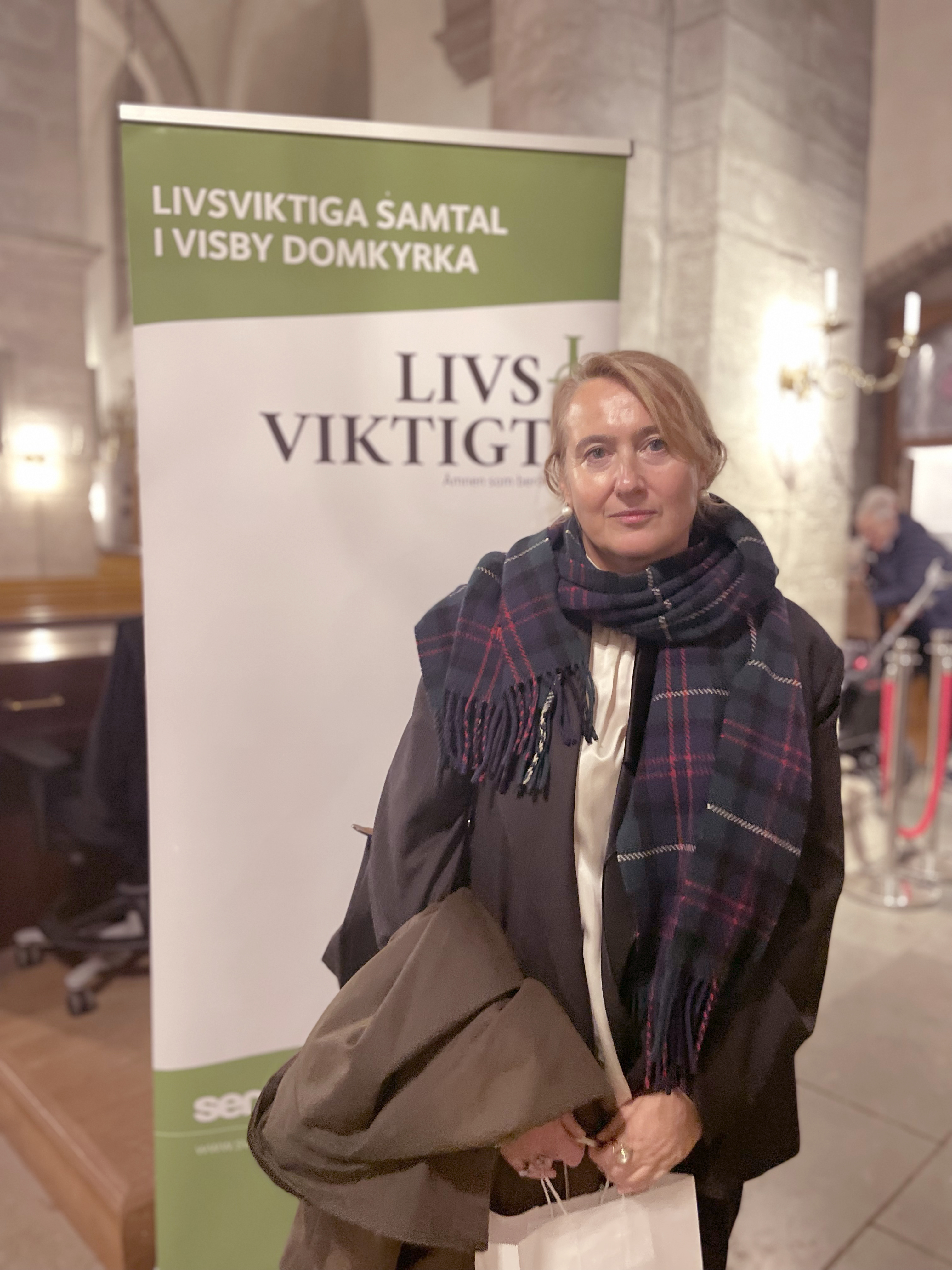 Porträttbild på Maria Engström framför en rollup med text om Livsviktigt.