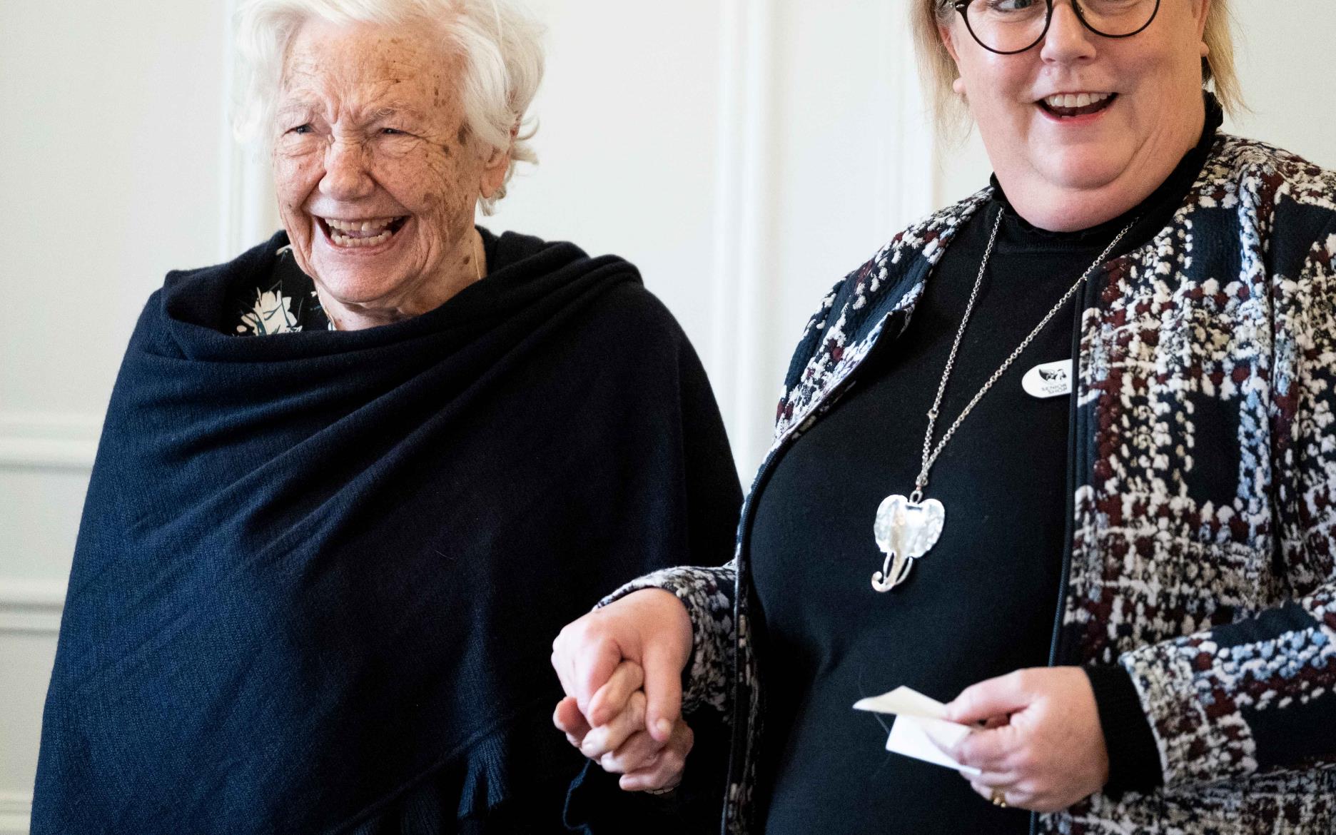 Två kvinnor som håller varandra i hand.