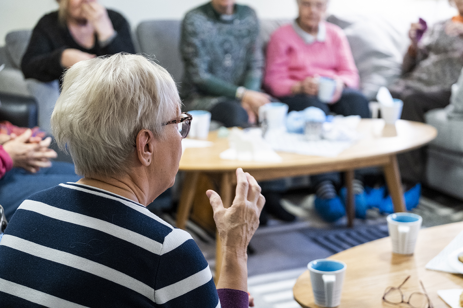 Några äldre damer sitter runt ett bord och fikar