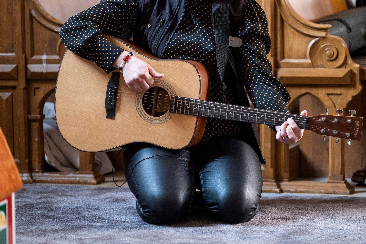 Person sitter på golvet och spelar gitarr