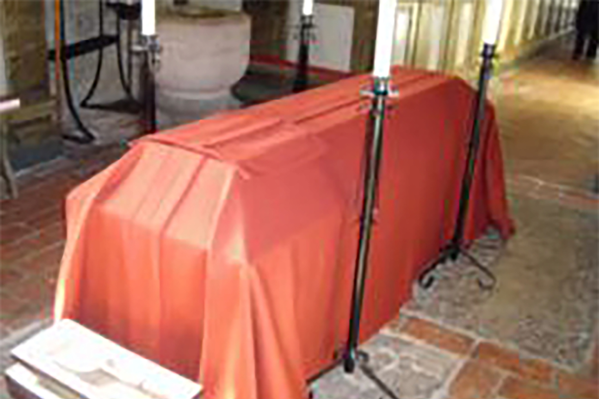 Rött bårtäcke placerat ovanpå en kista.