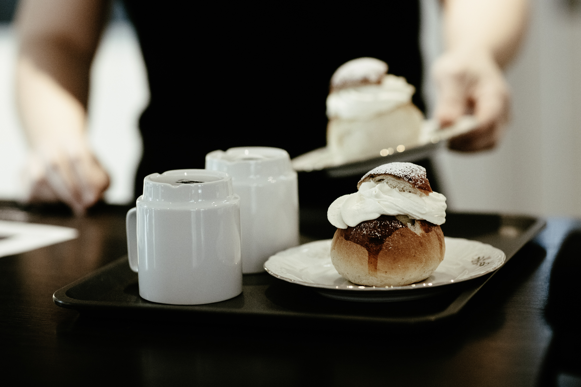 Två semlor med kaffe är beställt och ställs på en bricka vid kassadisken. 