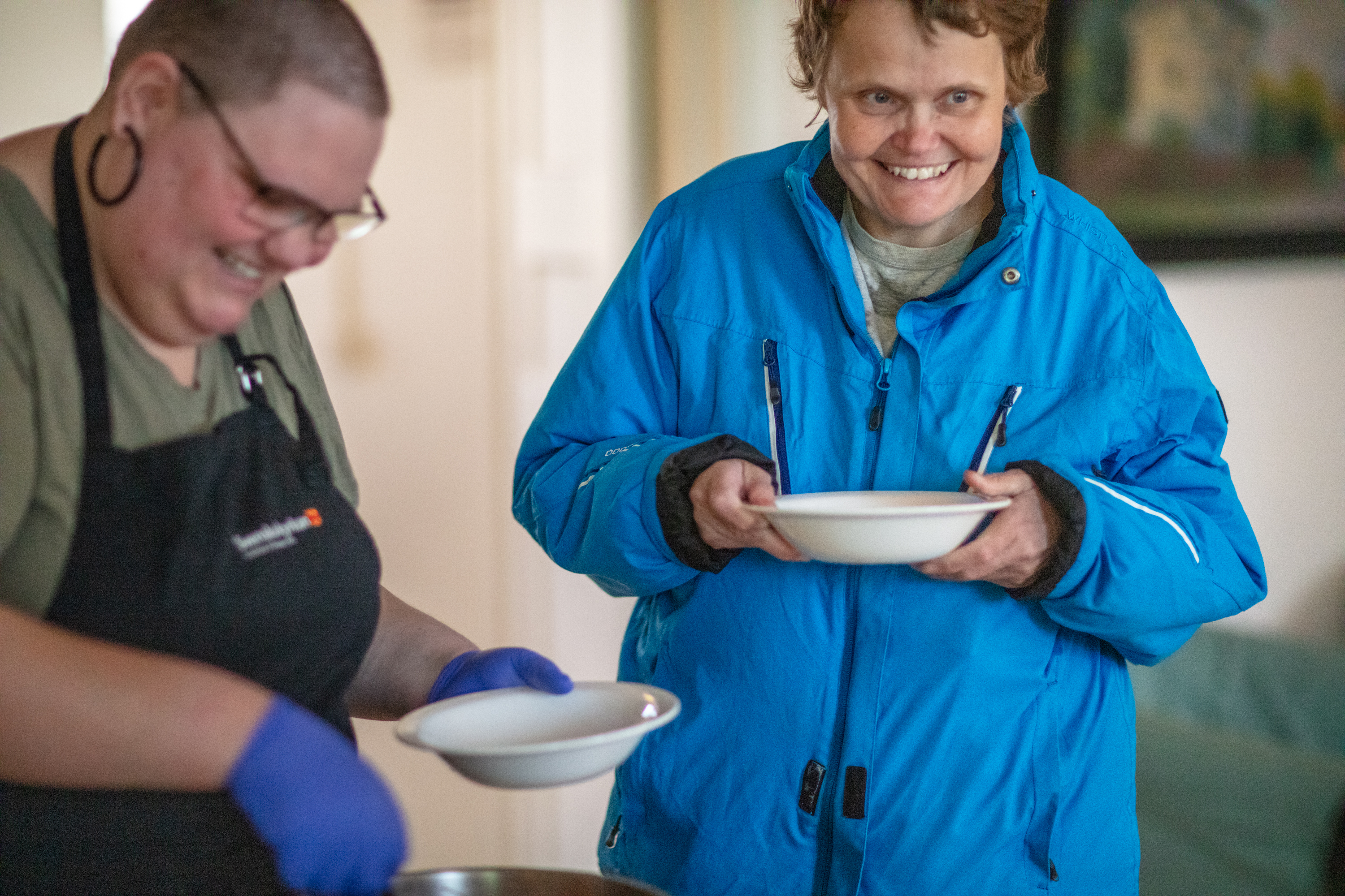 En person har precis fått soppa serverat i en tallrik som hon glatt håller i. 