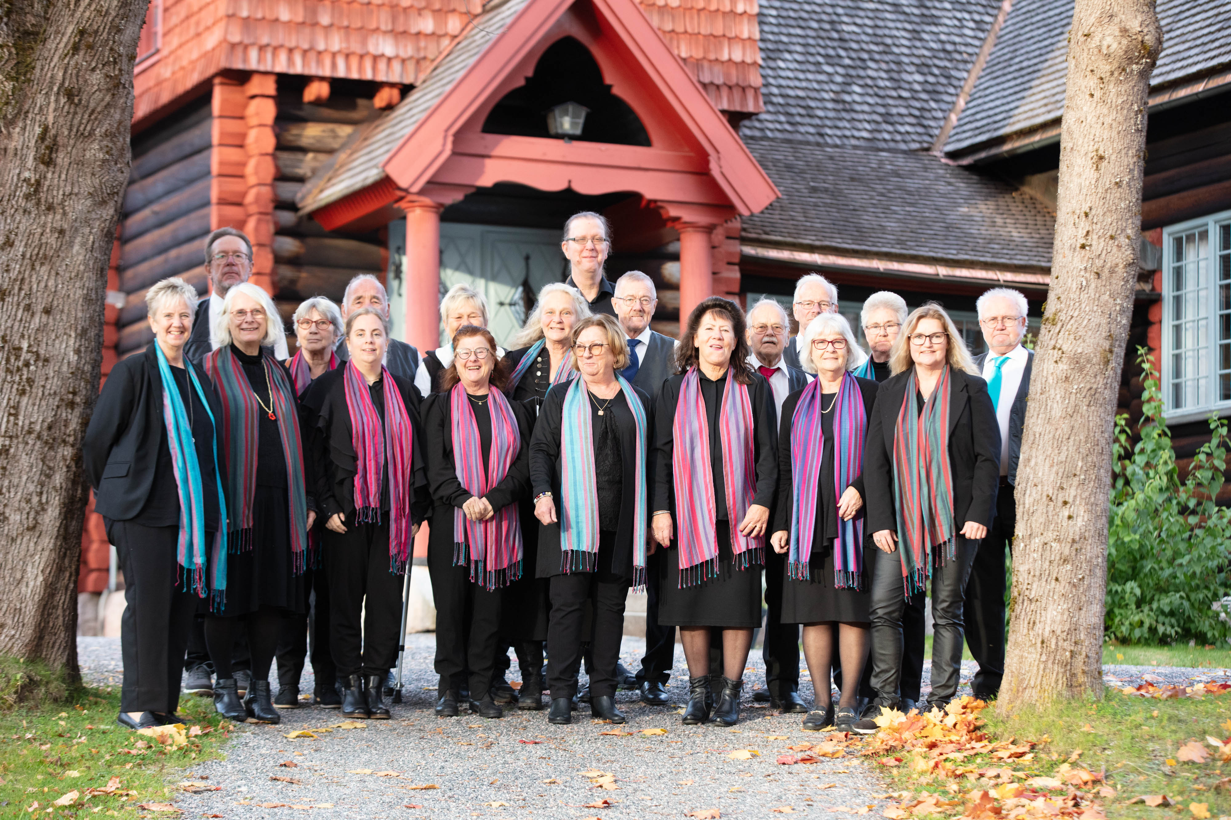 En hel kör står uppställd utanför Hörkens kyrka en sommardag