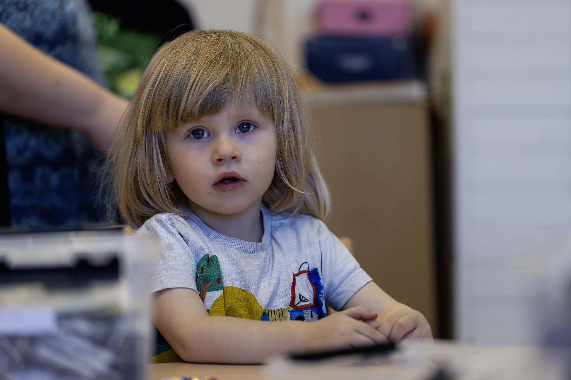 En liten pojke sitter vid ett bord och tittar in i kameran.