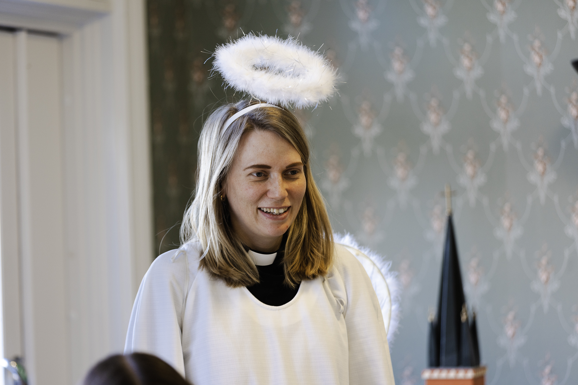 En präst har klätt ut sig till en ängel med gloria över huvudet