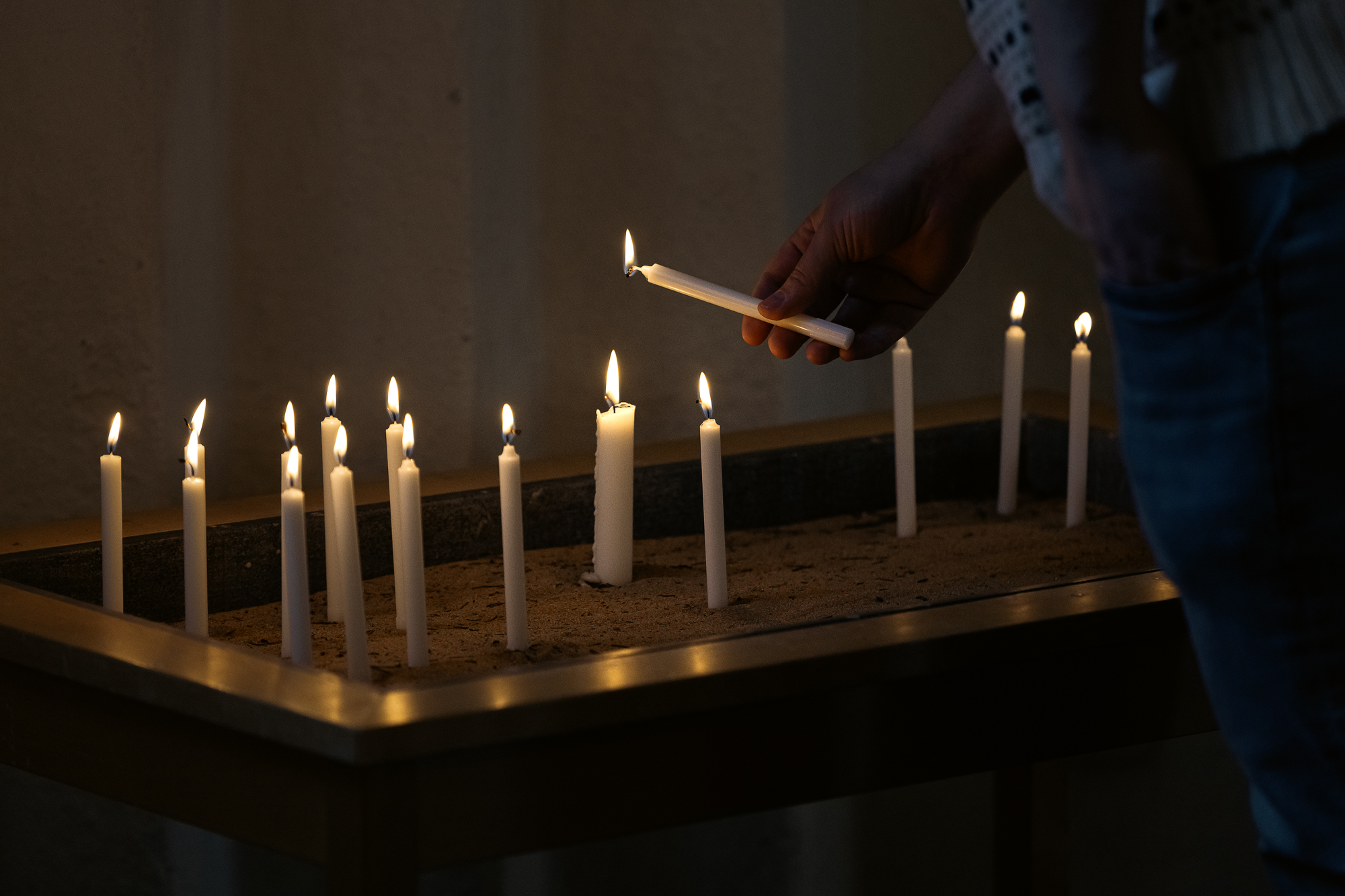 Många små ljus är nedstuckna i sandbordet och lågorna lyser varmt.