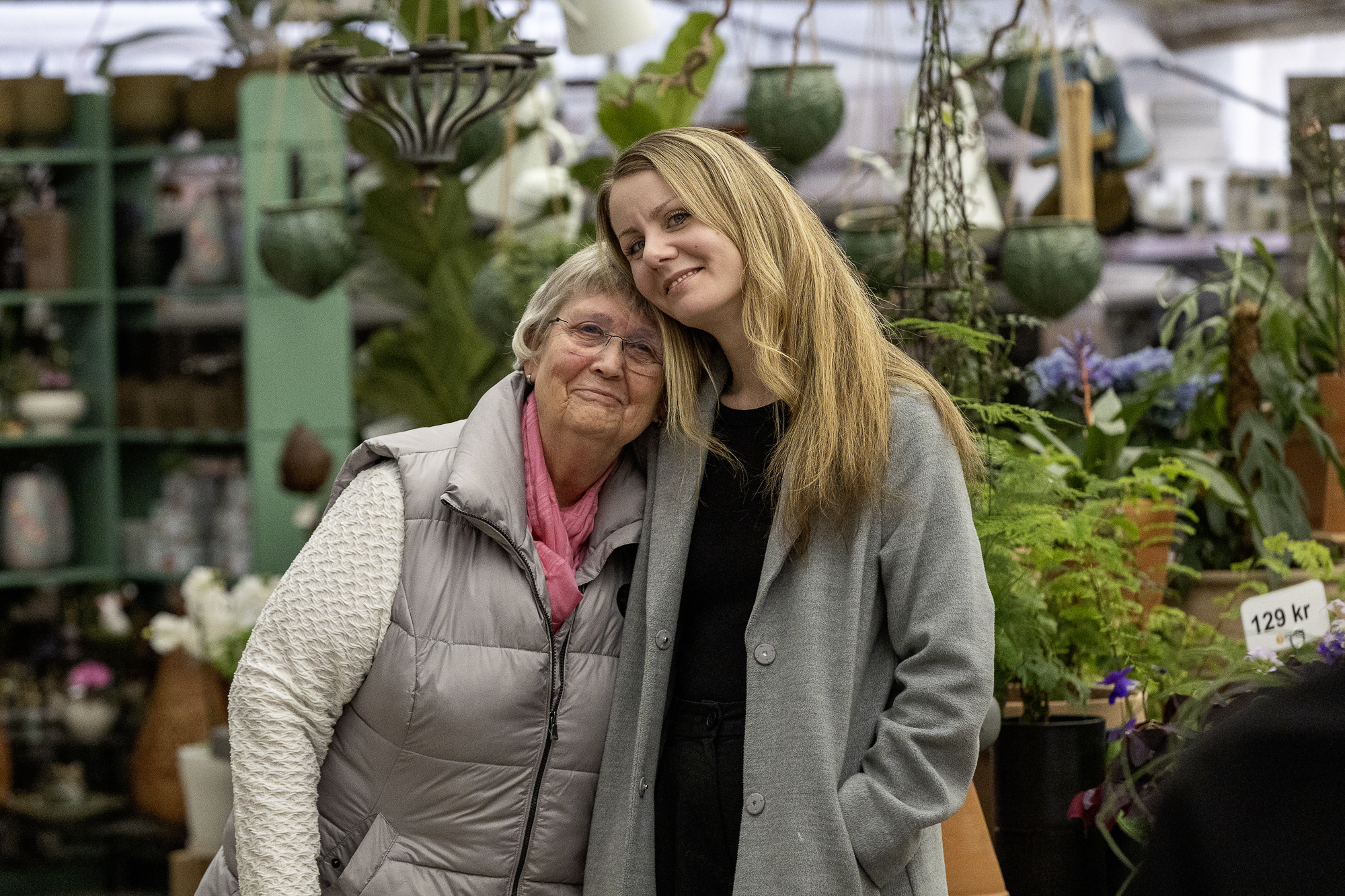 Två personer står i en blomsteraffär och lägger armen om den andre