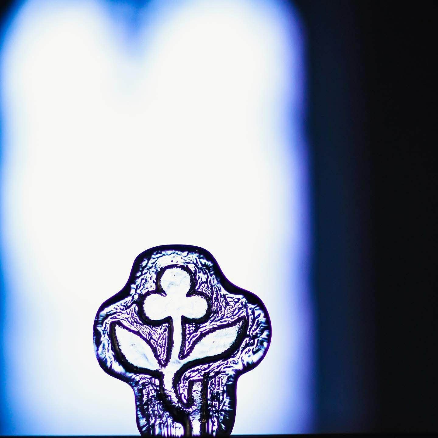 Sjukhuskyrkans symbol i form av ett glaskors med en blomma i. 