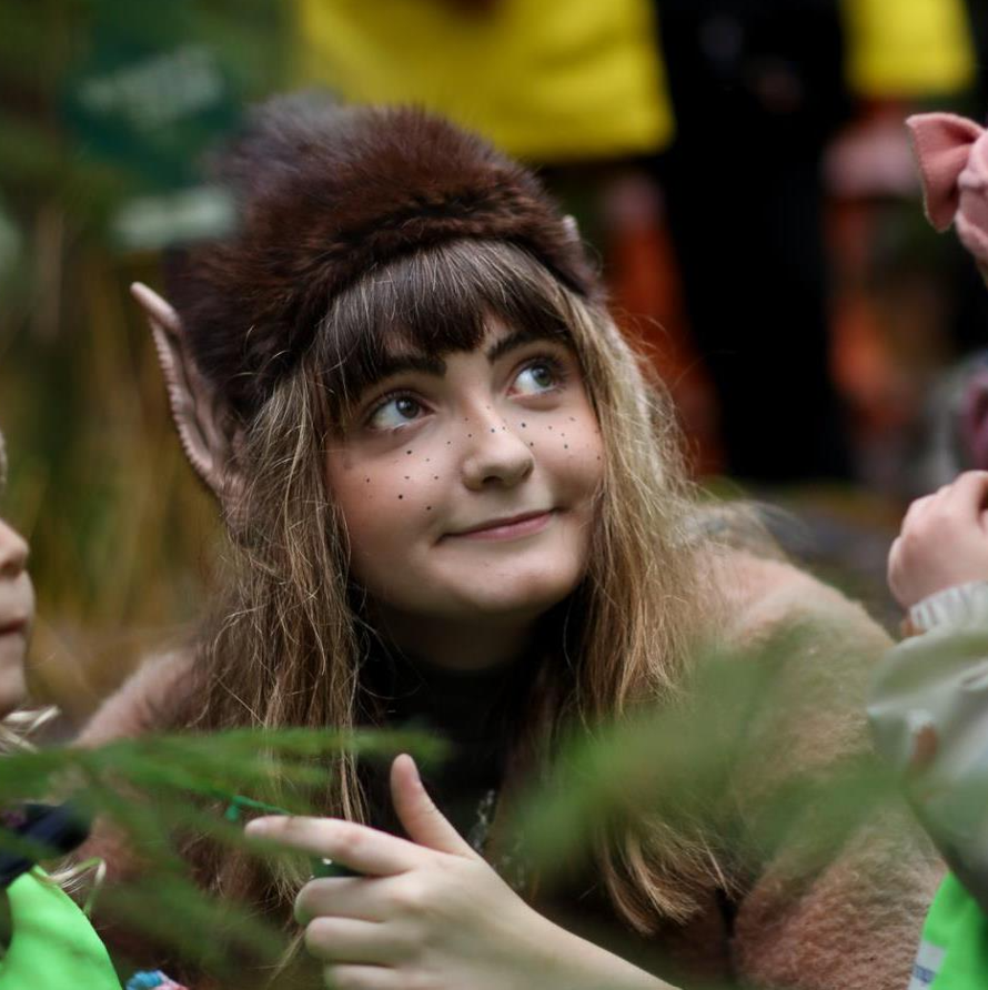 En tjej utklädd till troll möter nyfikna barn i skogen