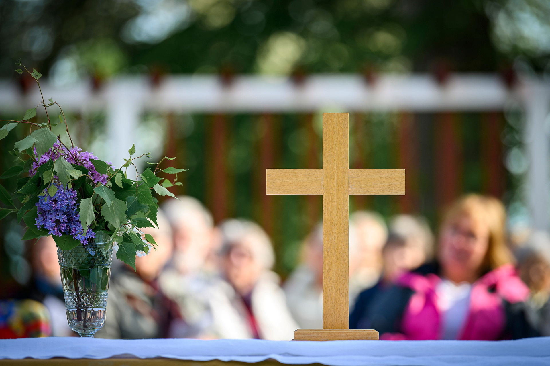 Ett träkors med personer i oskärpa i bakgrunden. 
