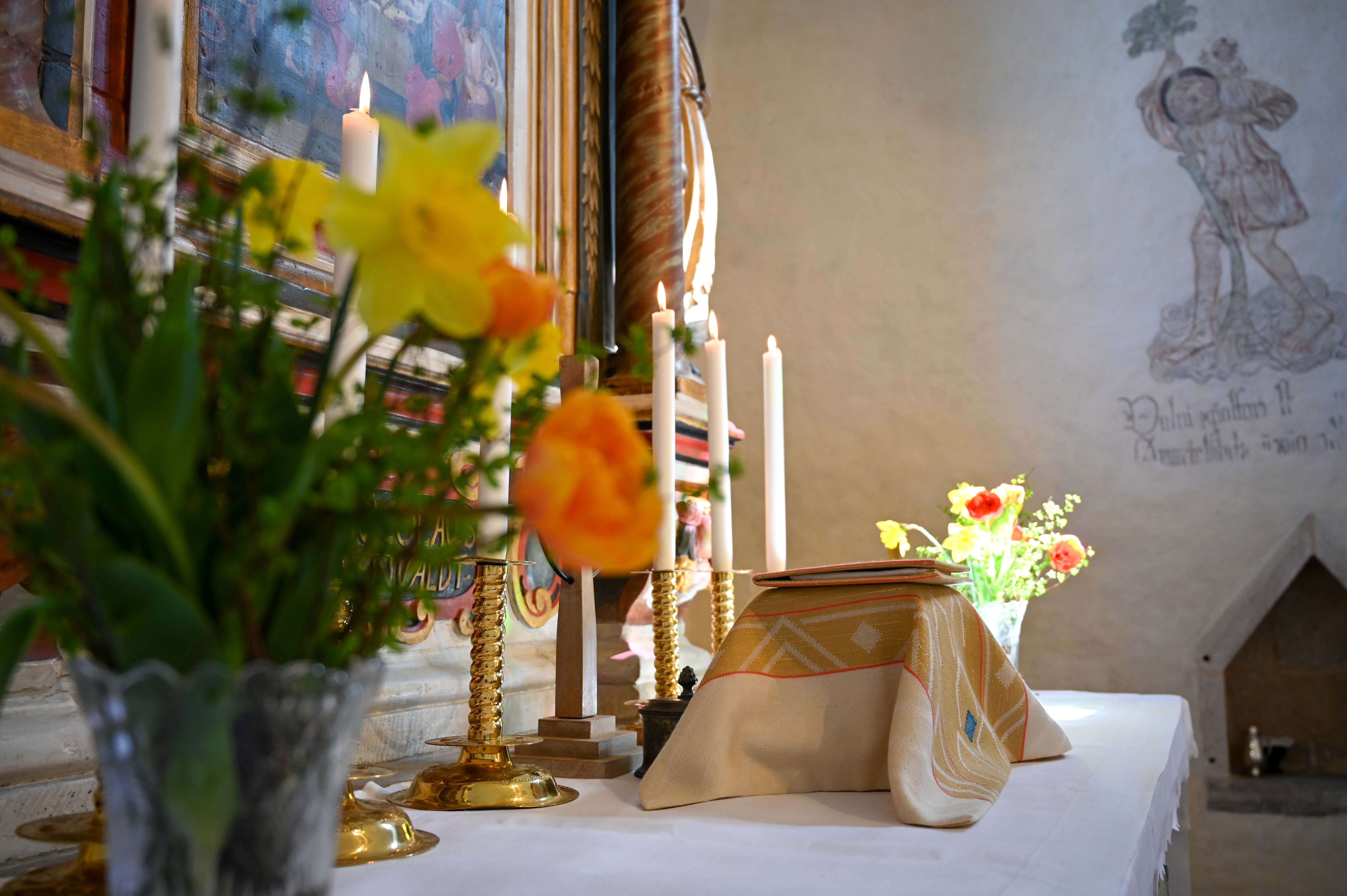 Altaret i Väte kyrka dukat med tända ljus och nattvard samt vaser med vårblomster