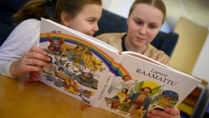 Två flickor läser ur barnens bibel på finska