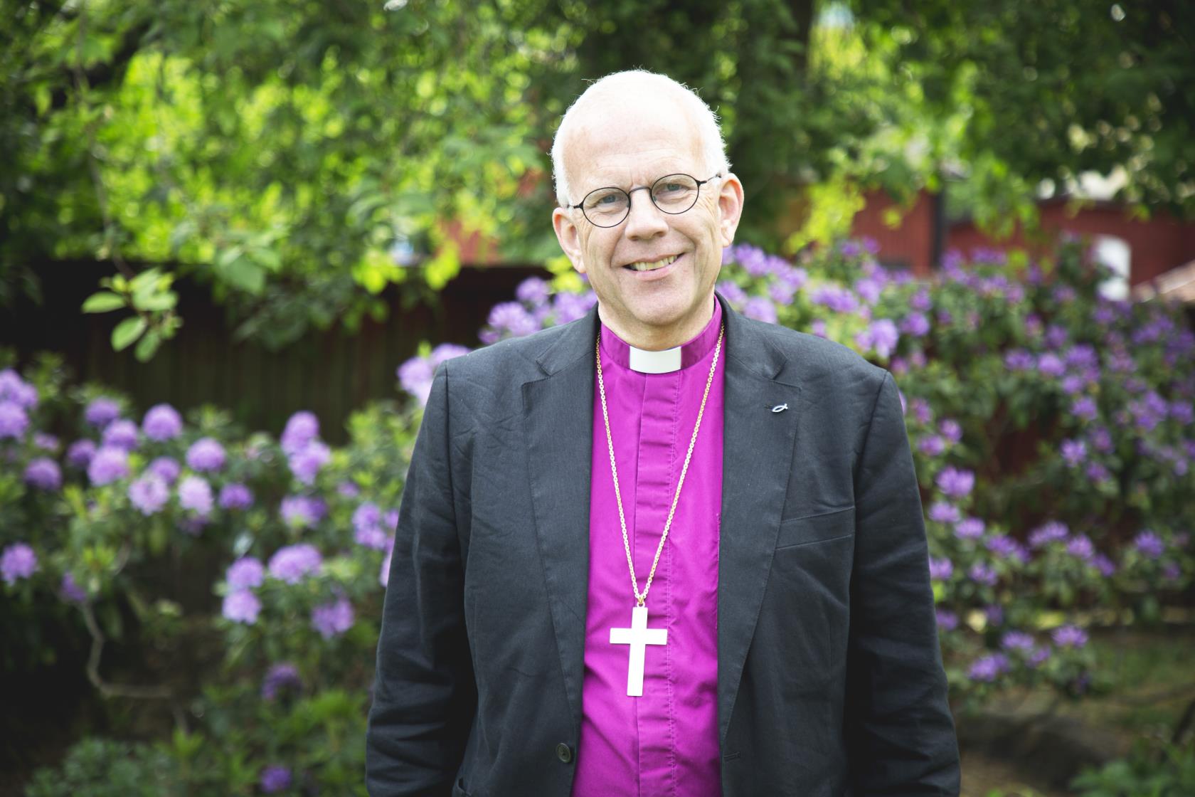 Bild på tillträdande biskop Martin Modéus ståendes framför blommande rhododendron