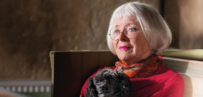 Konfirmanden Charlotte Sachs sitter i kyrkbänken i Danderyds kyrka med sin hund Noa.