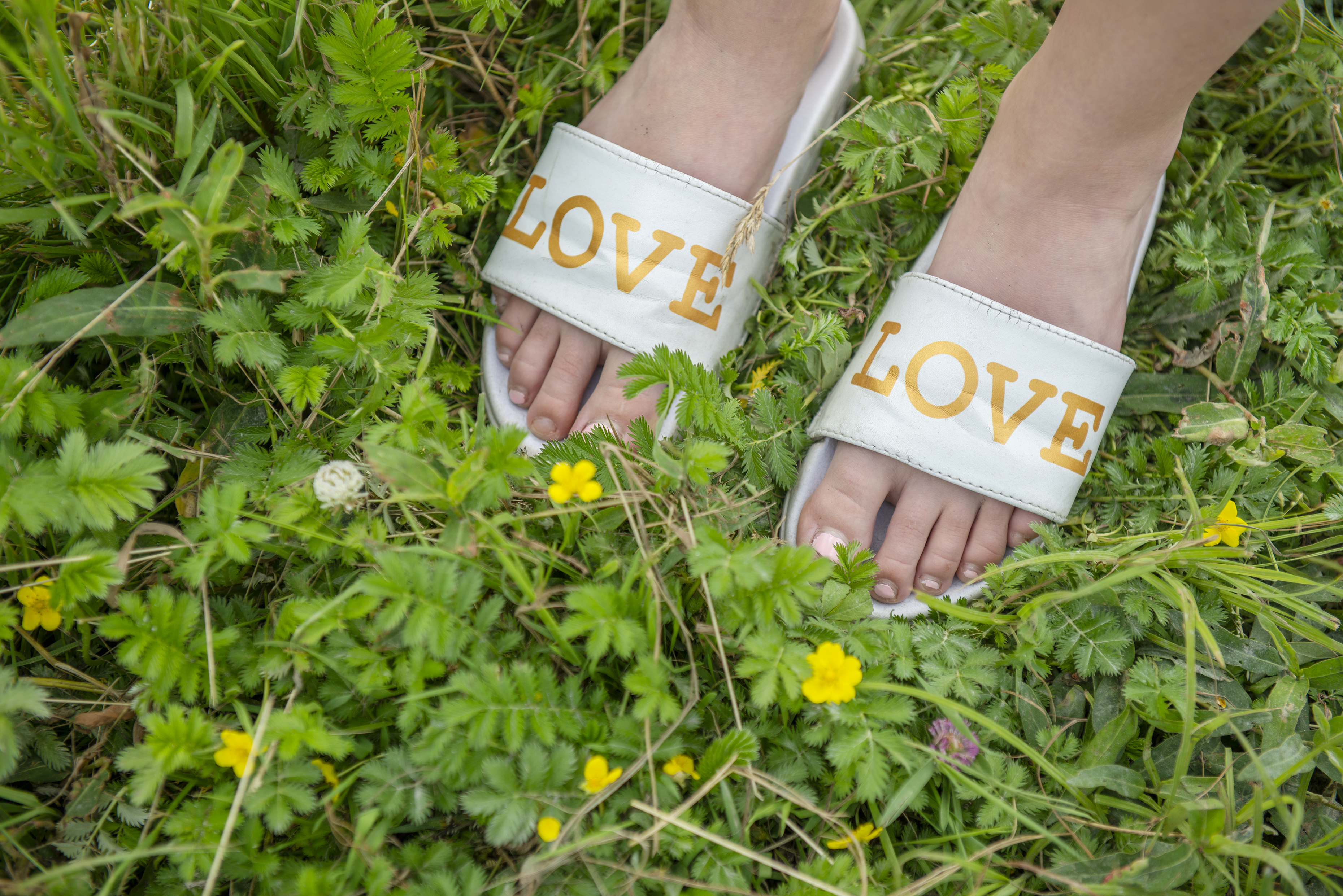Badskor i grönt gräs med texten love