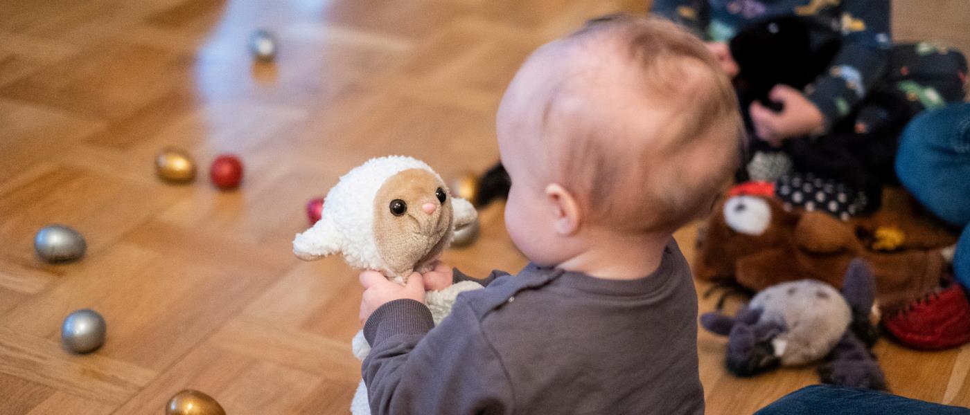 Bebis leker med ett gosedjur på golvet