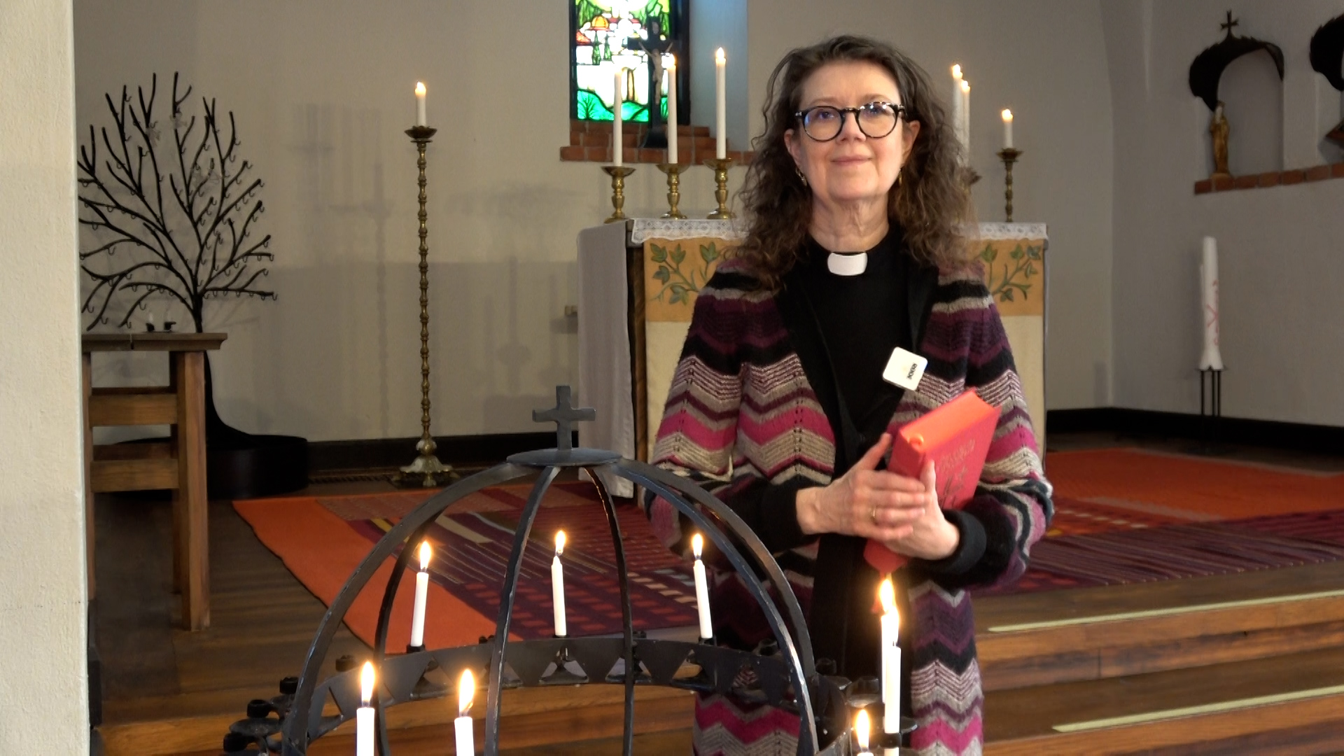 Präst står vid ljusbäraren i Enskede kyrka