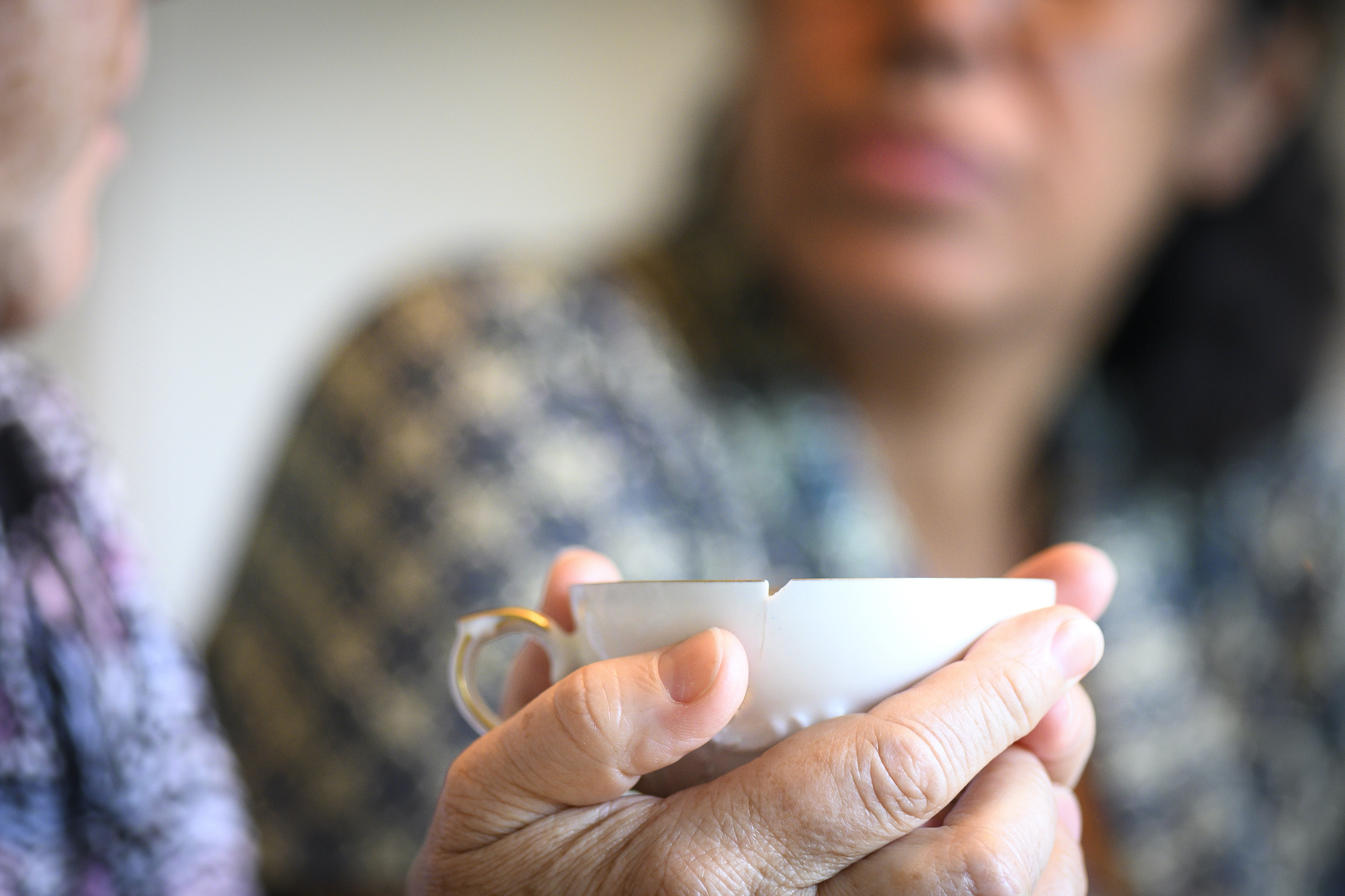 Två personer samtalar, kaffekopp i förgrunden
