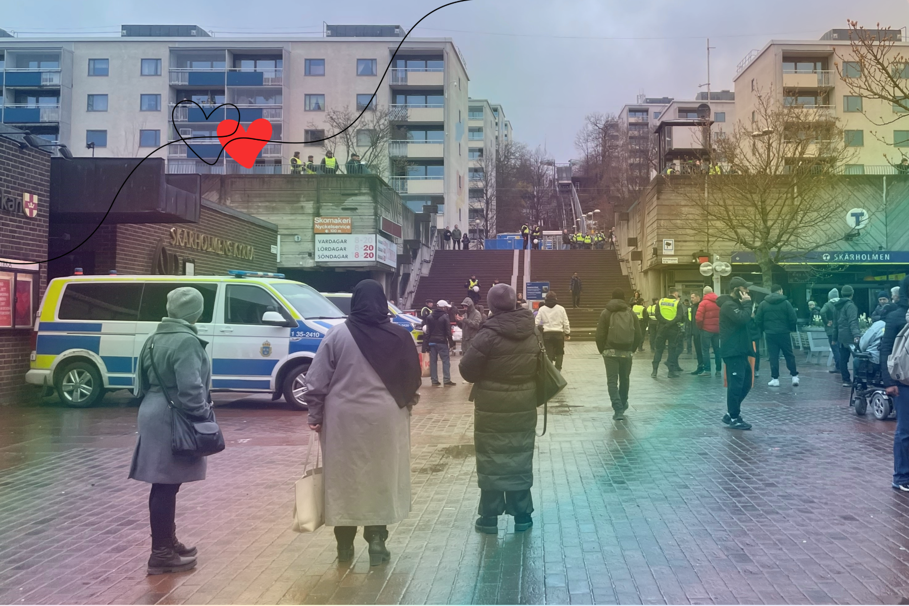 Tre muslimska kvinnor närmst i bild, med ryggen vända mot kameran, blickar ut över platsen där Koranen ska komma att brännas. Till vänster står en piketbuss från polisen och till höger en stor skara människor som kommit för att titta och motdemonstrera.