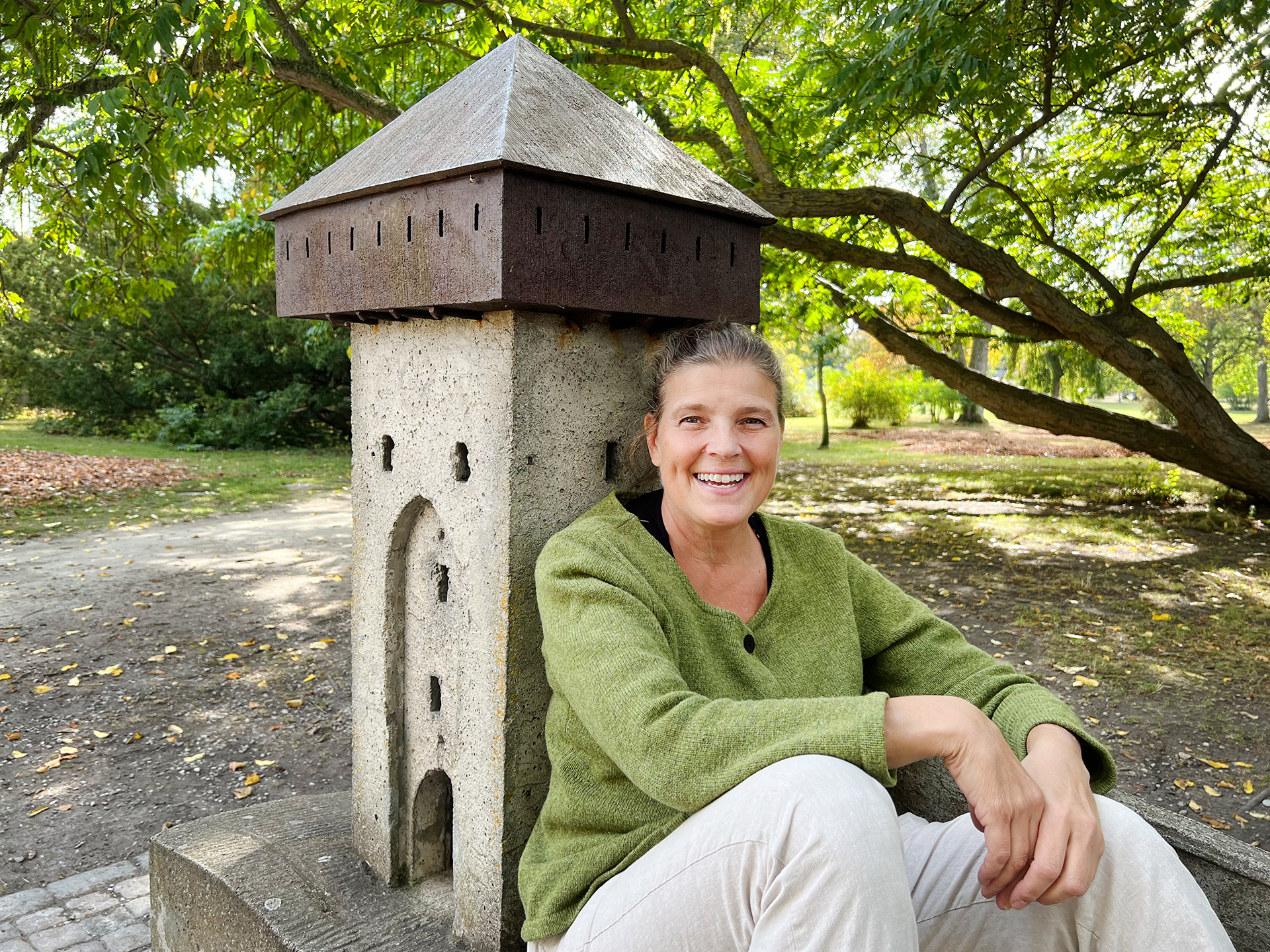 Kvinna sitter och ler på miniatyr av ett torn