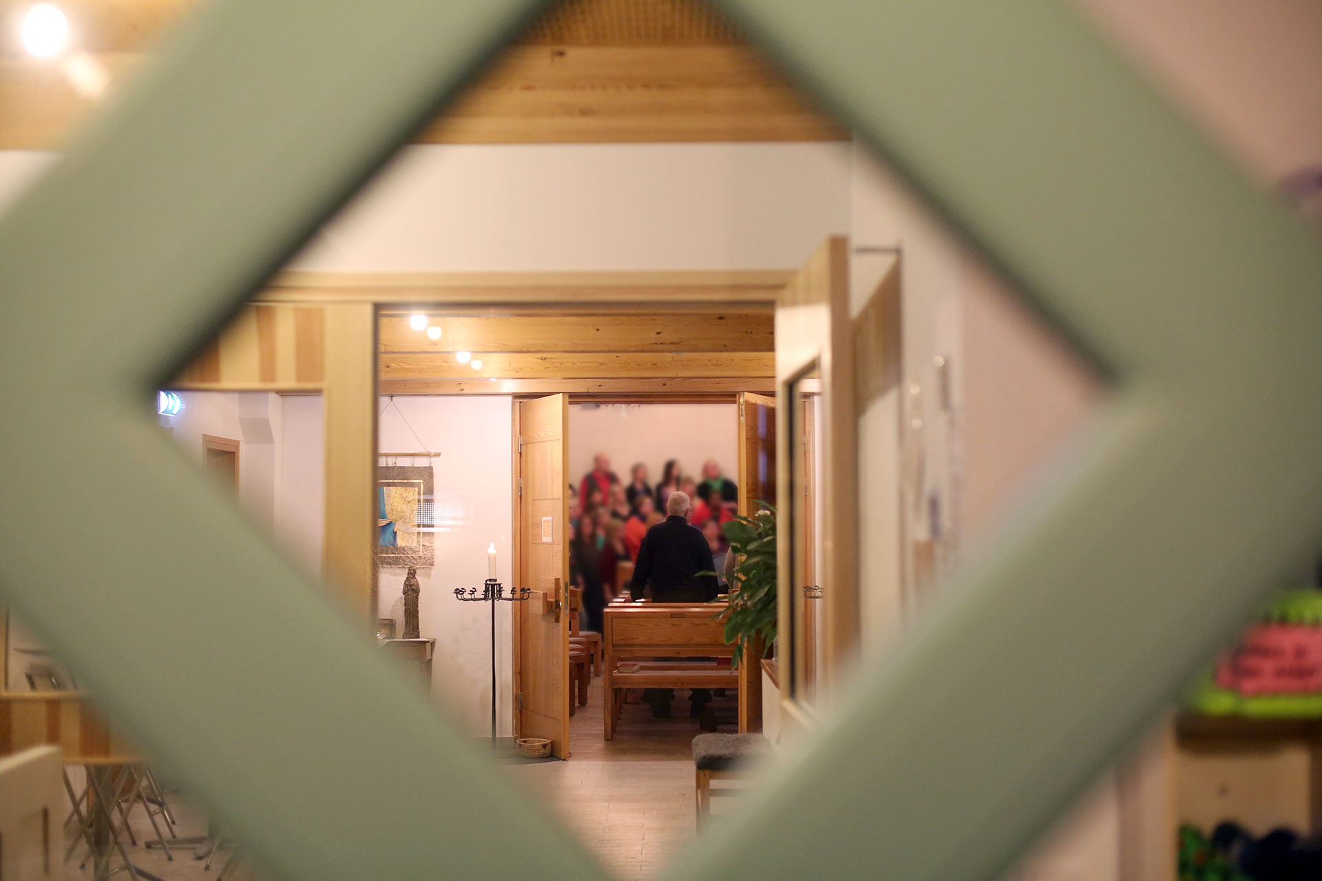 Fotograferat genom ytterdörren med fönsterbågarna i förgrunden och längst bak i bilden syns en kör längs med väggen i kyrkorummet.