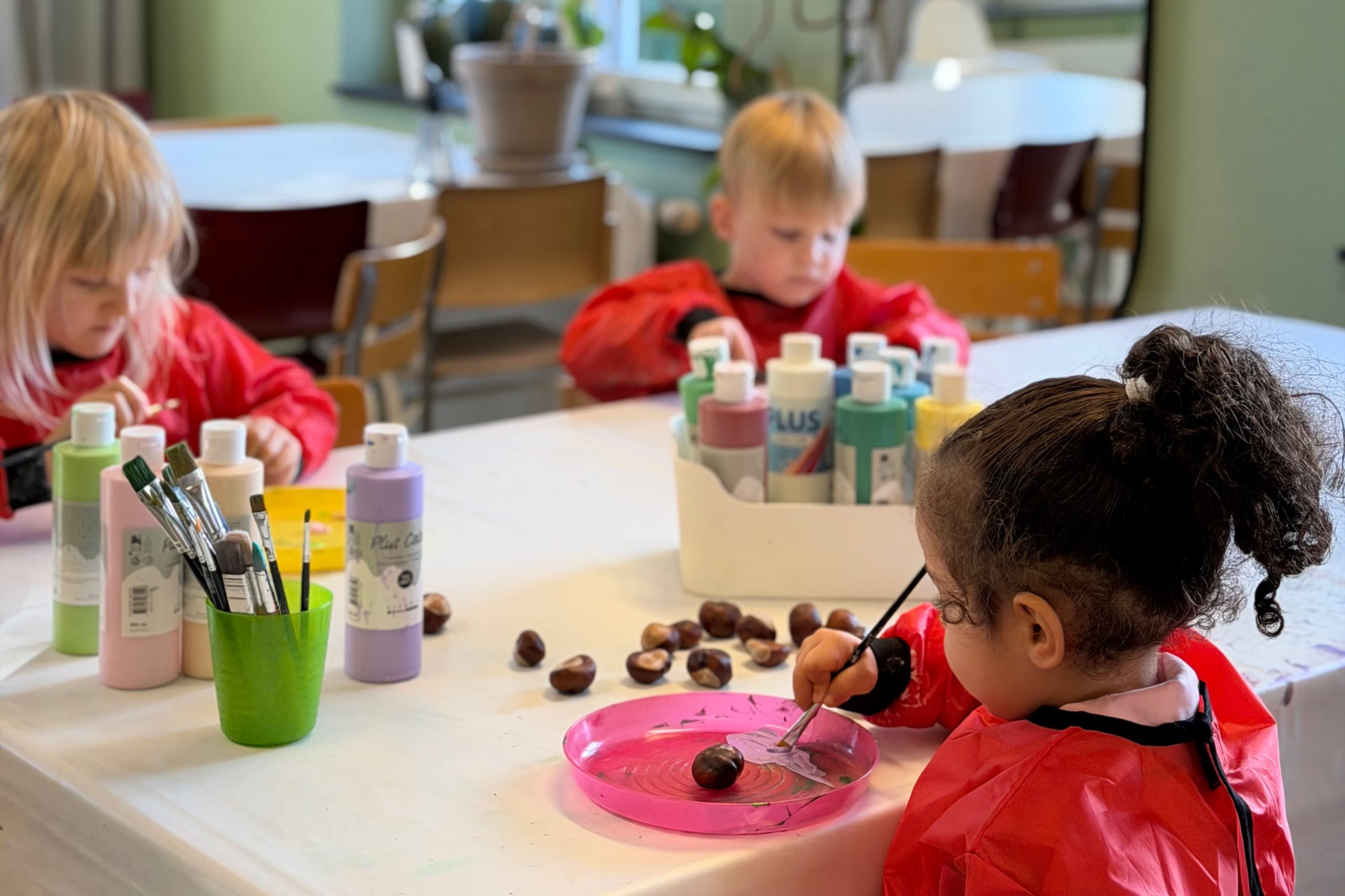 Tre barn målar runt ett bord.