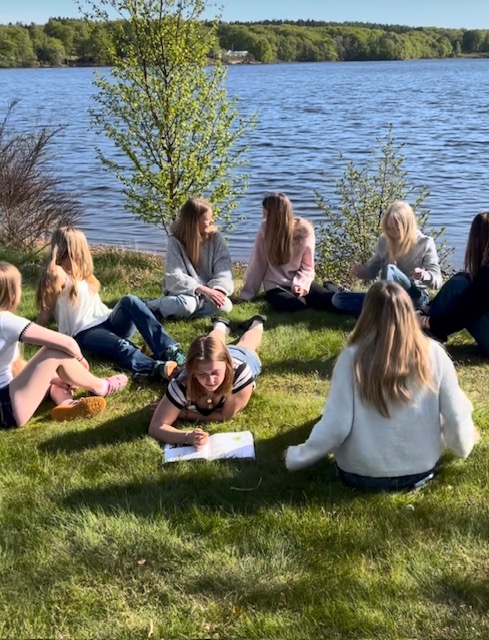 Konfirmander i gräset vid en sjö