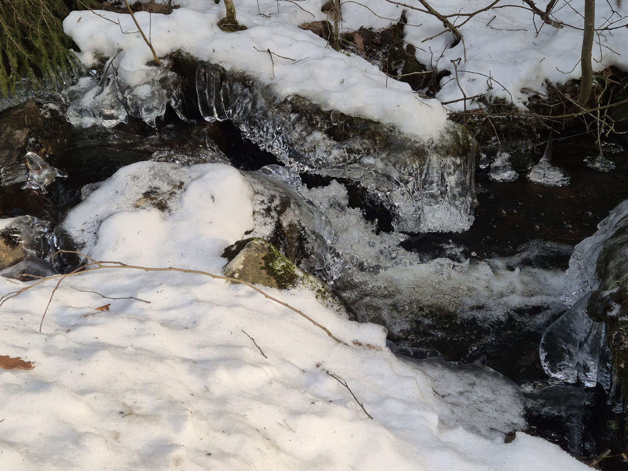 Forsande bäck med snö och isformationer