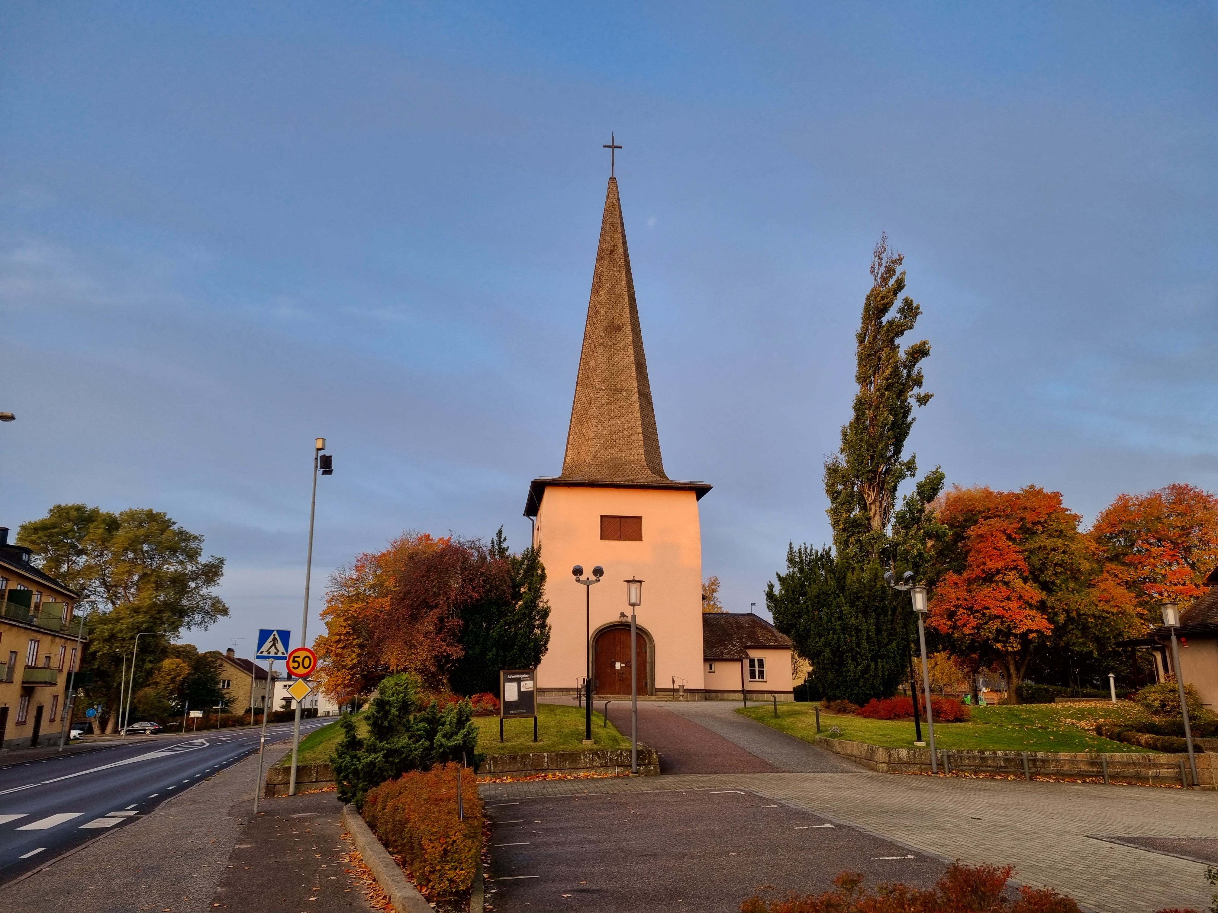 Rosa kyrka omgiven av träd i höstfärger