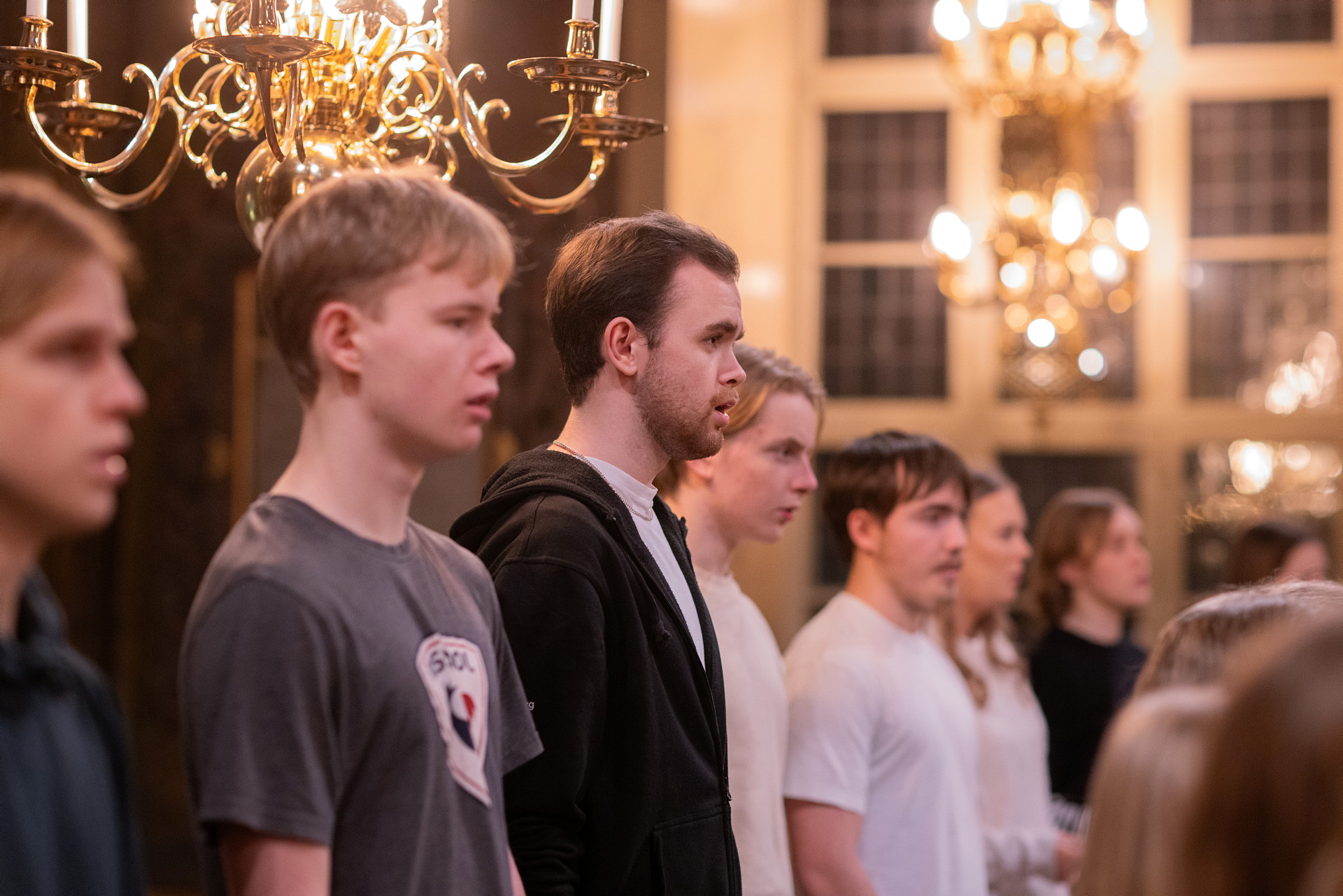 Bilden visar killar och tjejer som sjunger i en kör i en kyrka.