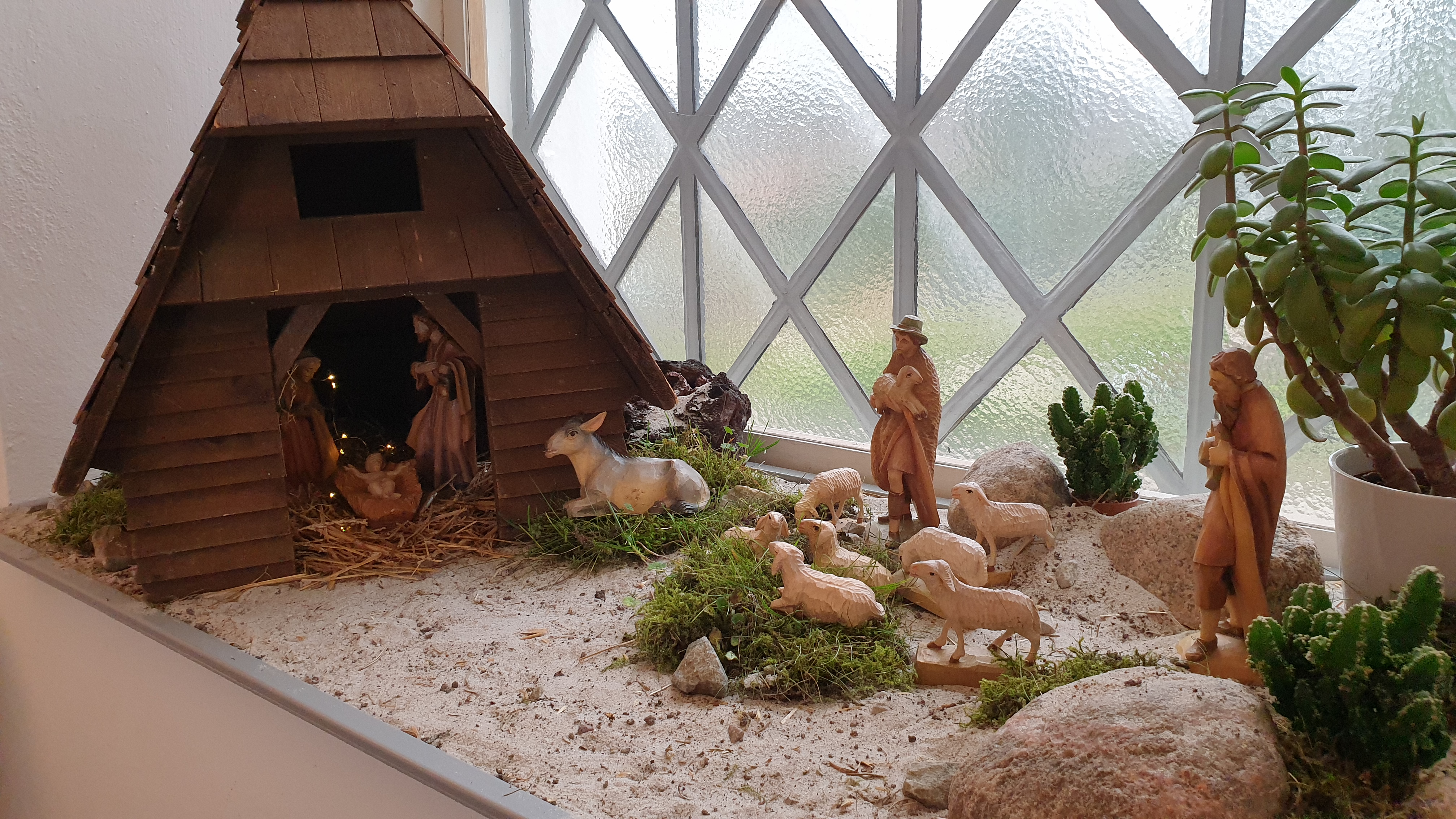 Julkrubba med figurer och stall i trä, i fönsterkarmen i Brågarps kyrka