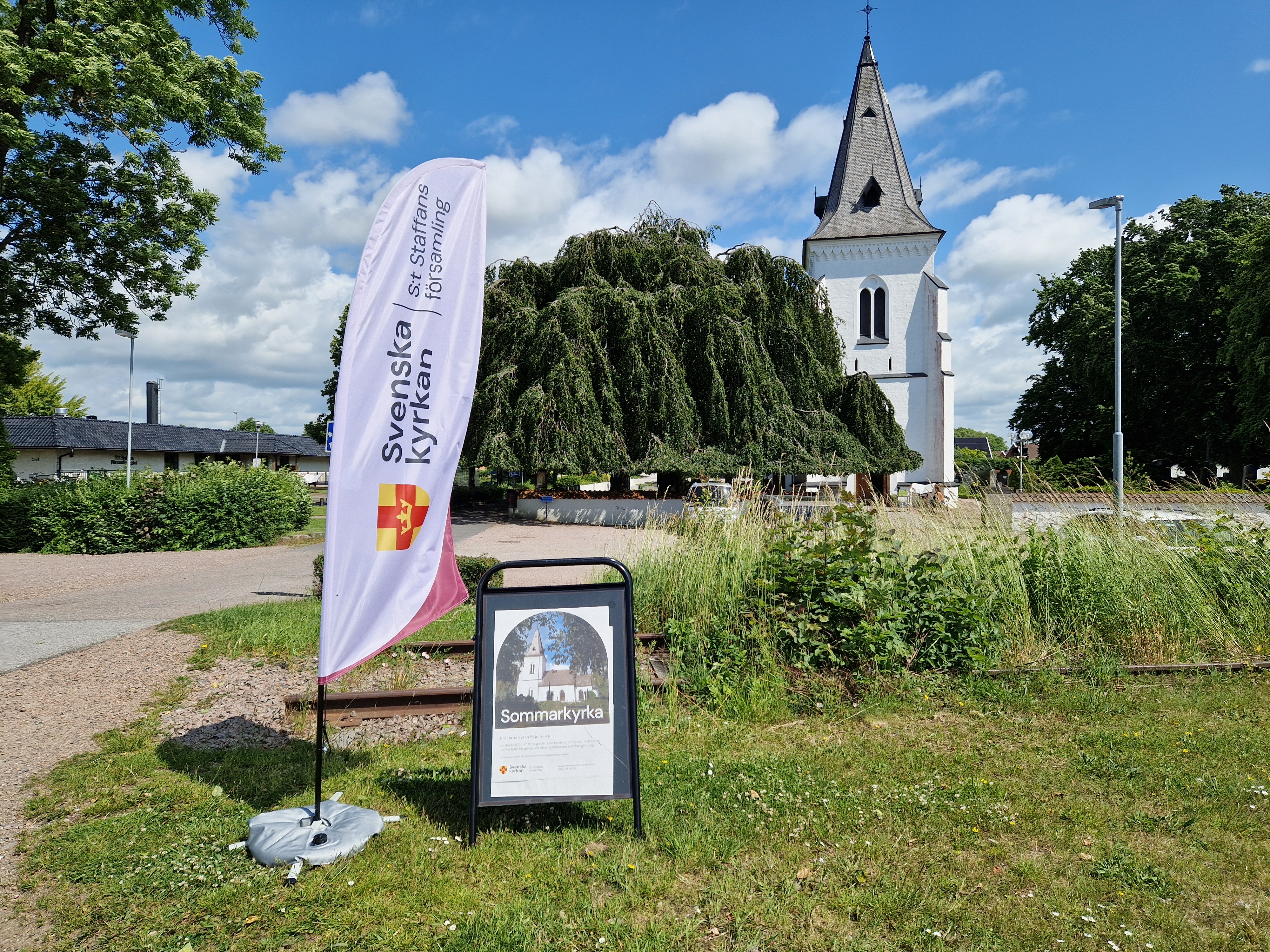 Beachflagga och skylt om sommarkyrka framför Brågarps kykra.