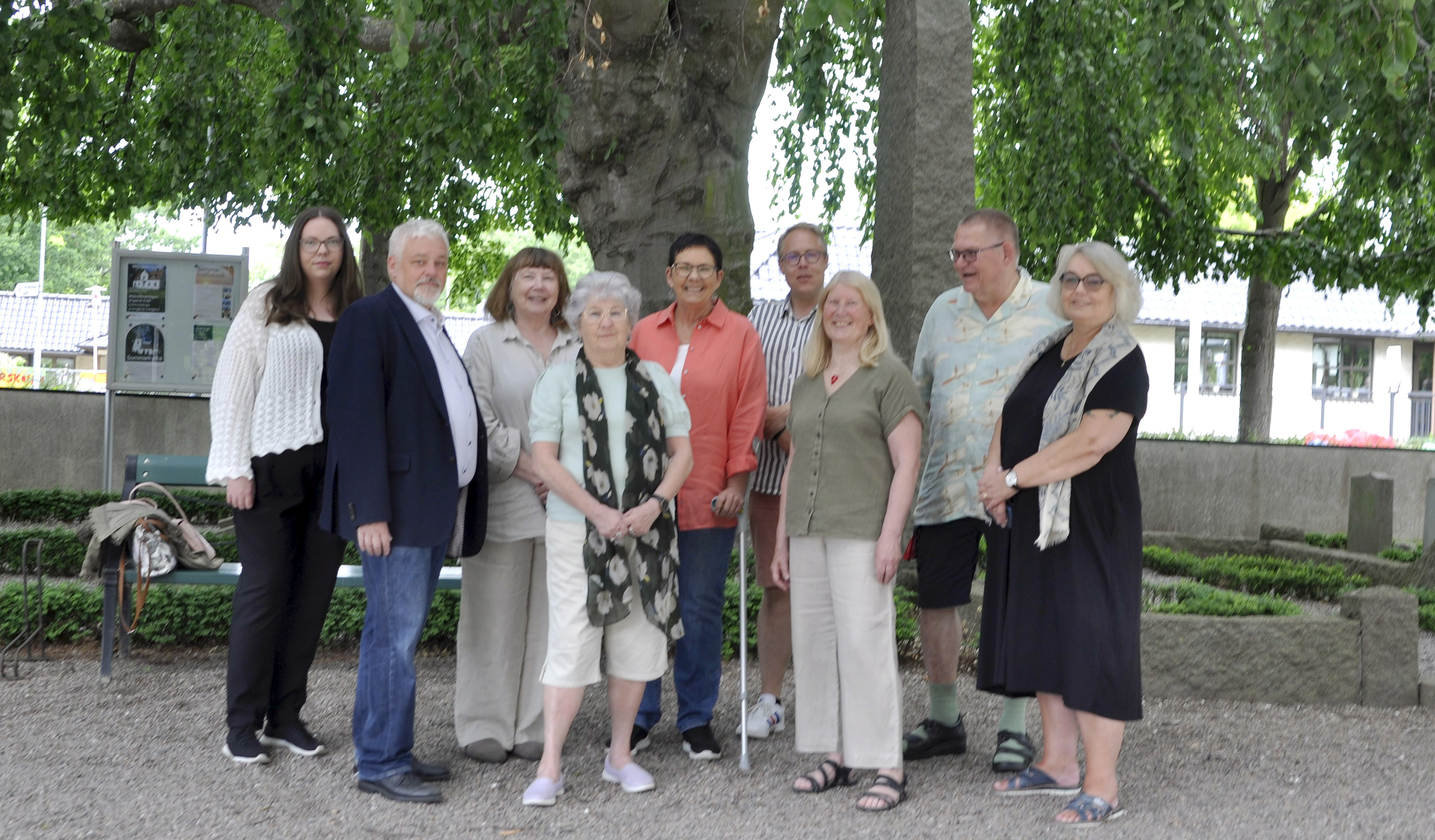 Nio leende personer under hängboken på Brågarps kyrkogård..