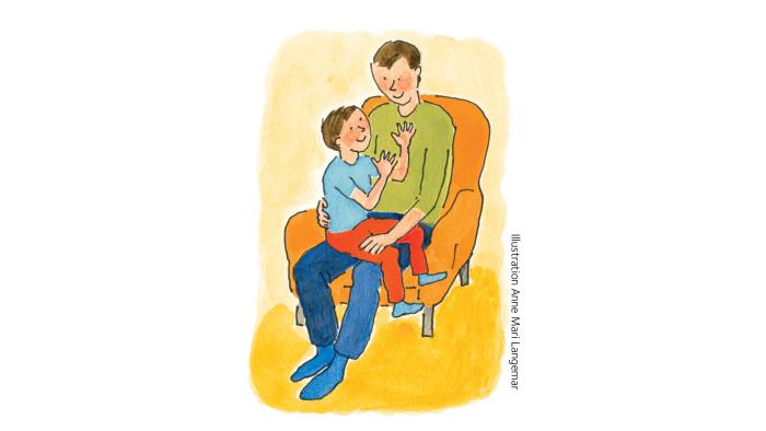 Förälder med ett barn i knäet sitter i en fåtölj.