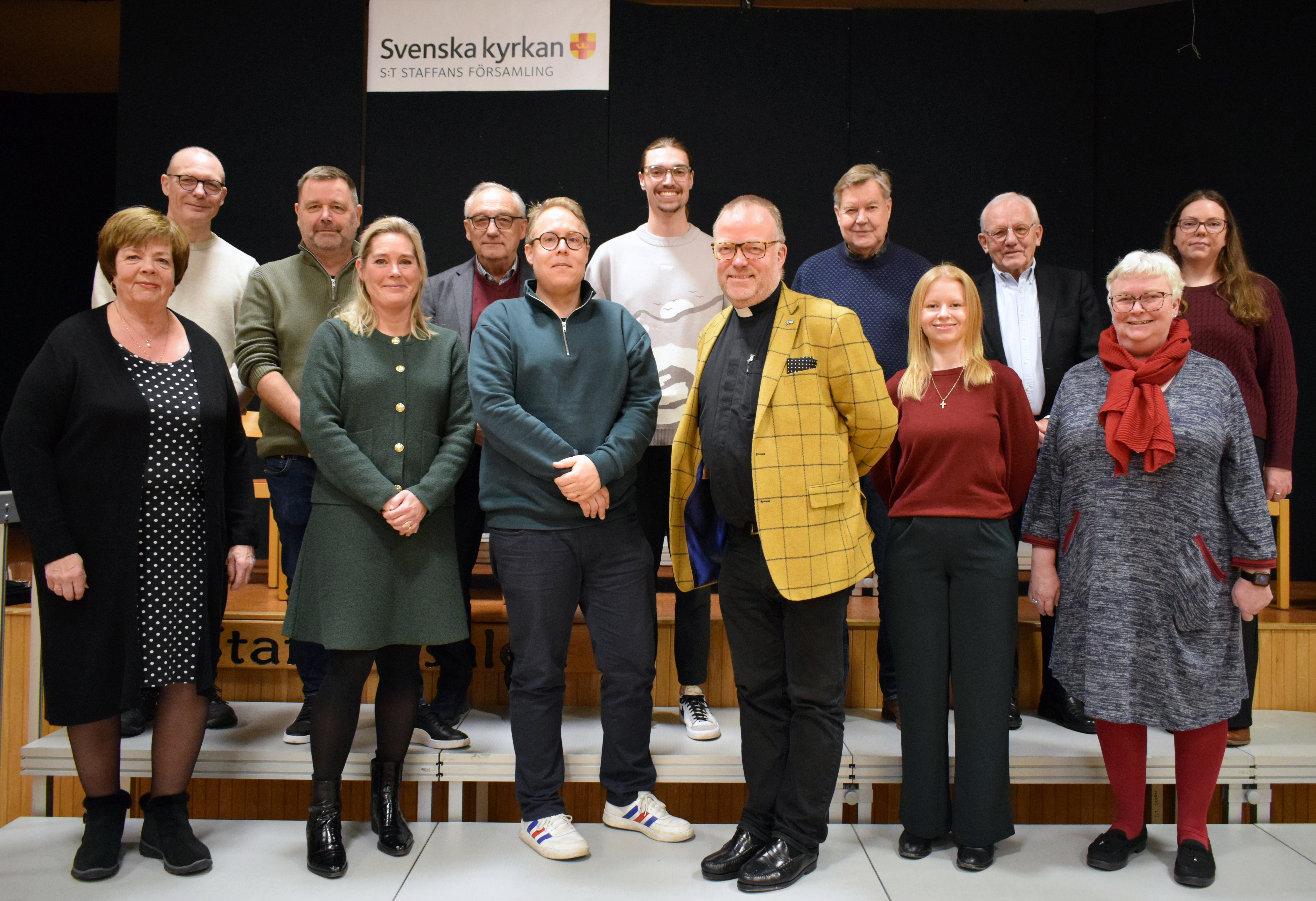 13 glada personer uppställda till gruppbild.