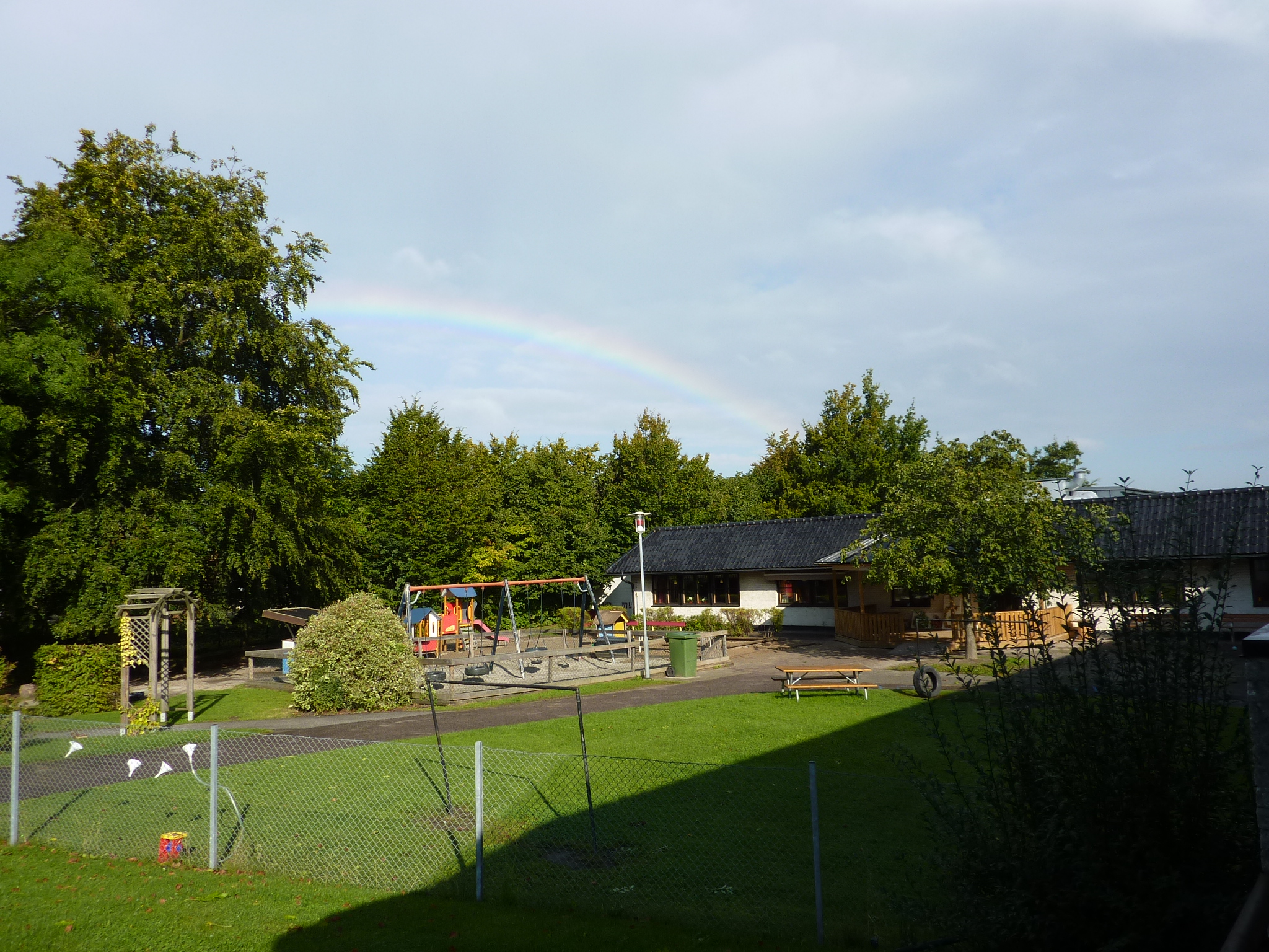 Förskolan Axet utifrån med en regnbåge ovanför taket.