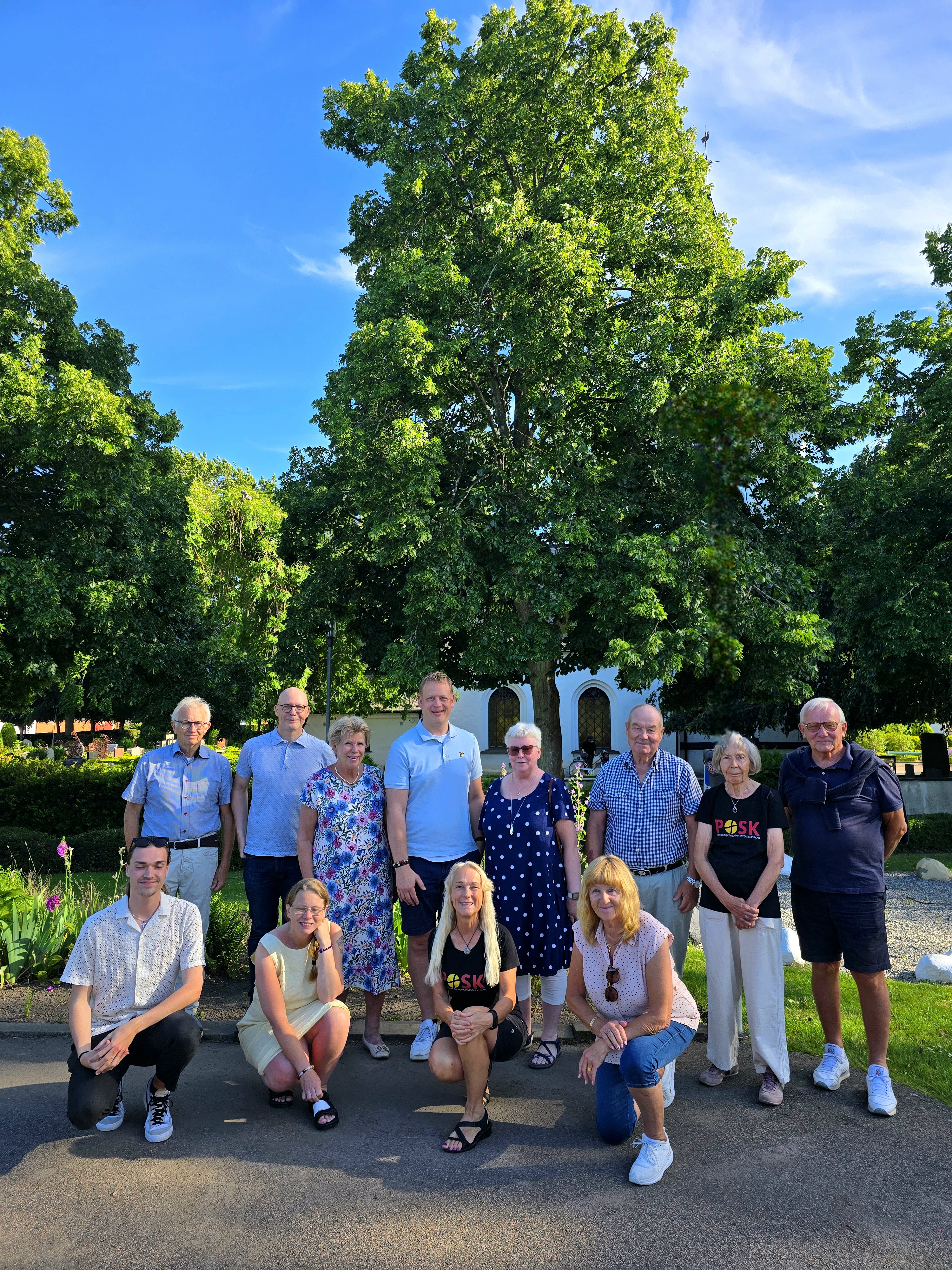 Tolv leende personer framför Brågarps kyrka.
