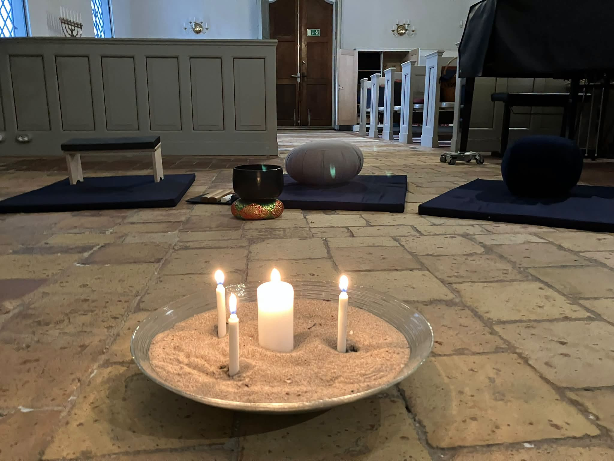 ljusfat med tre brinnande ljus står på kyrkgolvet