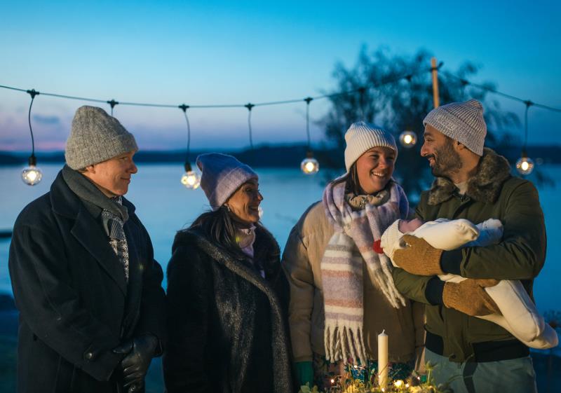 En familj håller utomhusdop för sitt barn i Svenska kyrkan