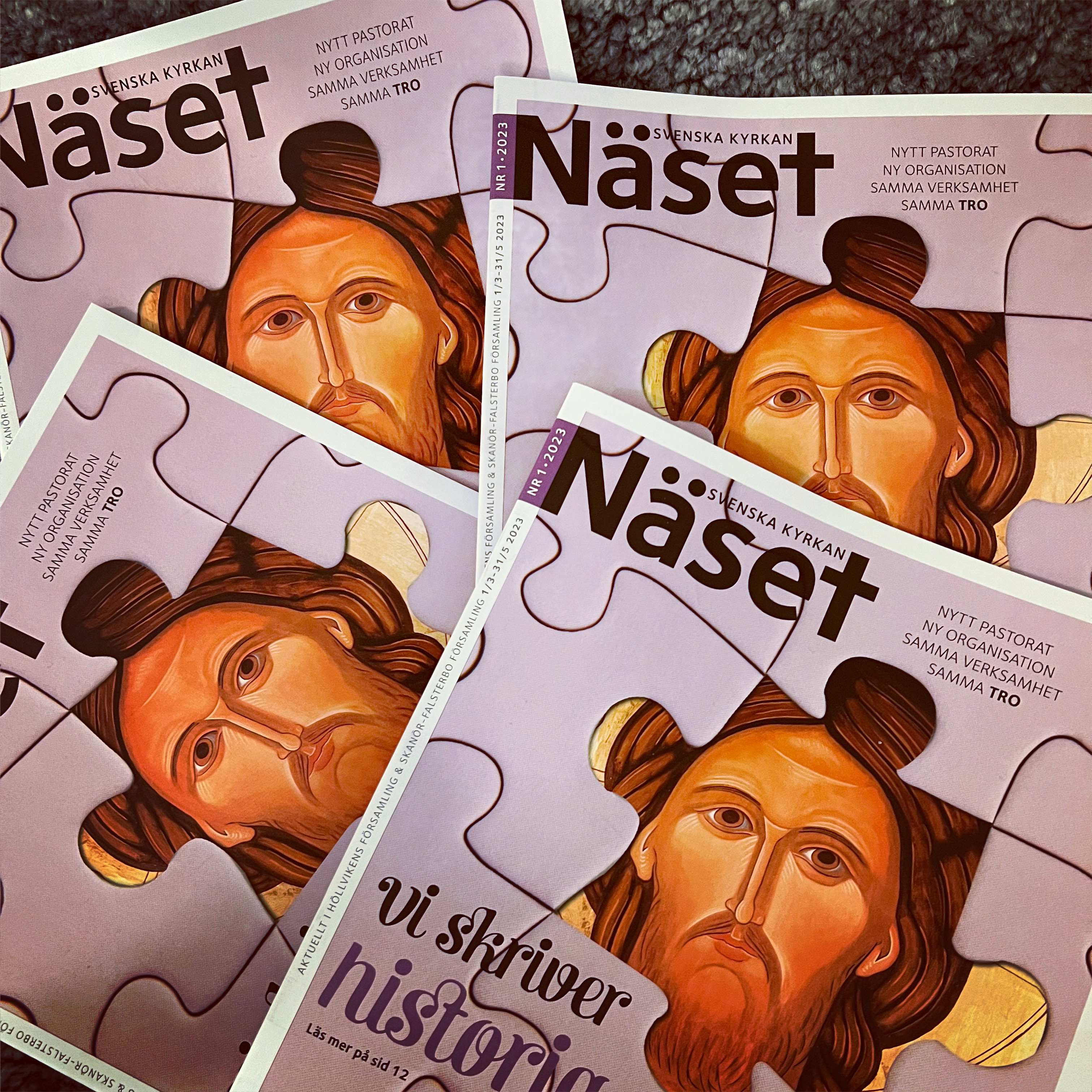 Fyra nummer av församlingstidningen Näset ligger på grå djurfäll.