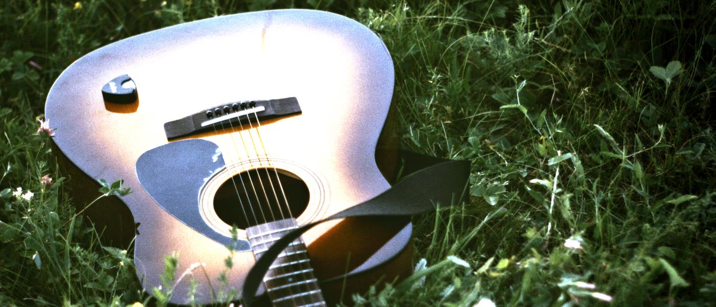 Gitarr som ligger i gröngräset.