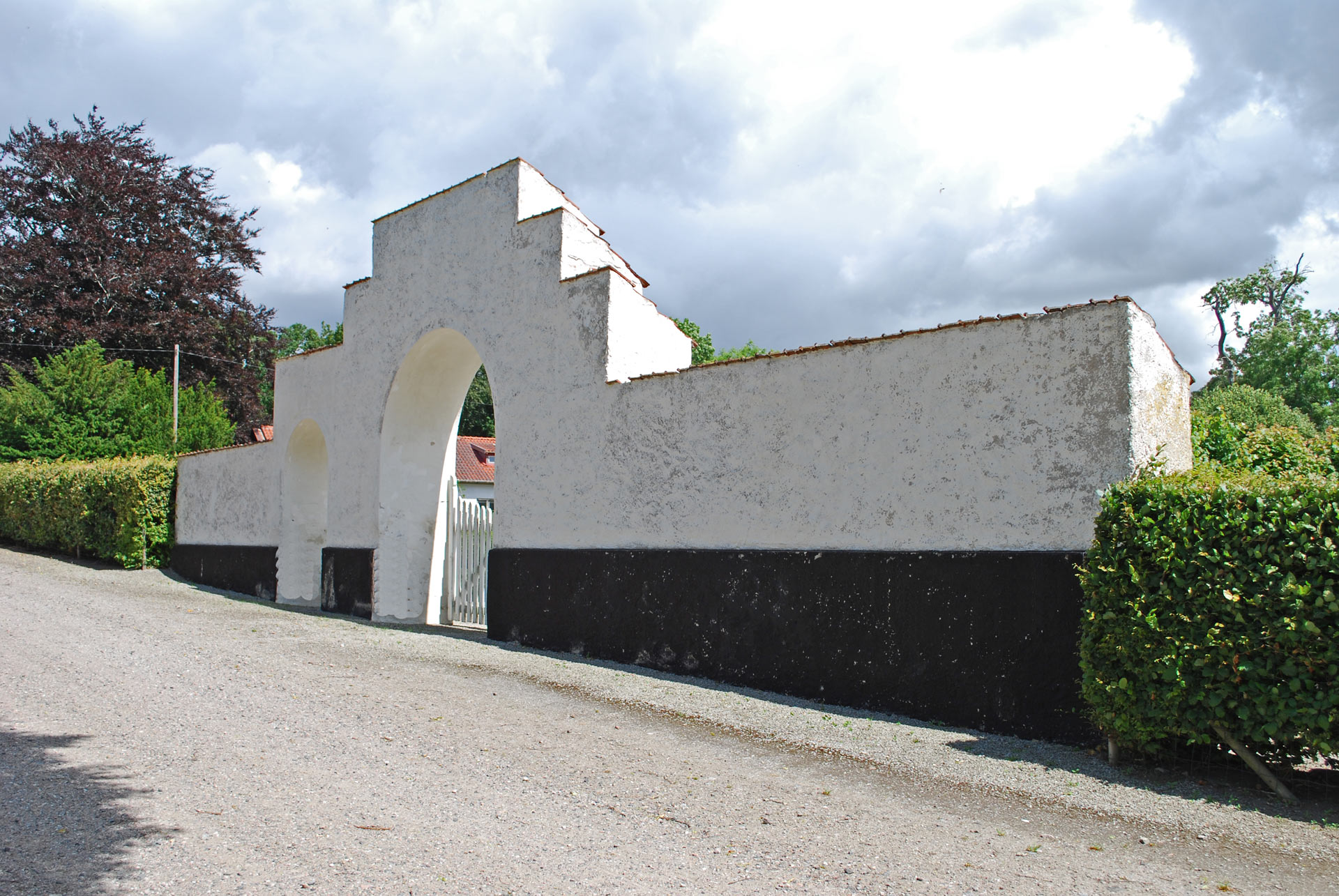 Kyrkogårdsmuren Nya kyrkogården Tosterup, vitkalkad portal och häck