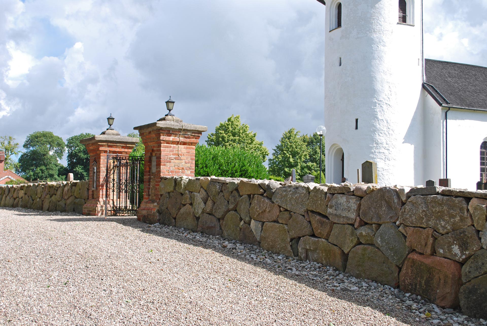 Kyrkogårdsmuren vid Bollerups kyrka med grinden in till kyrkogården.