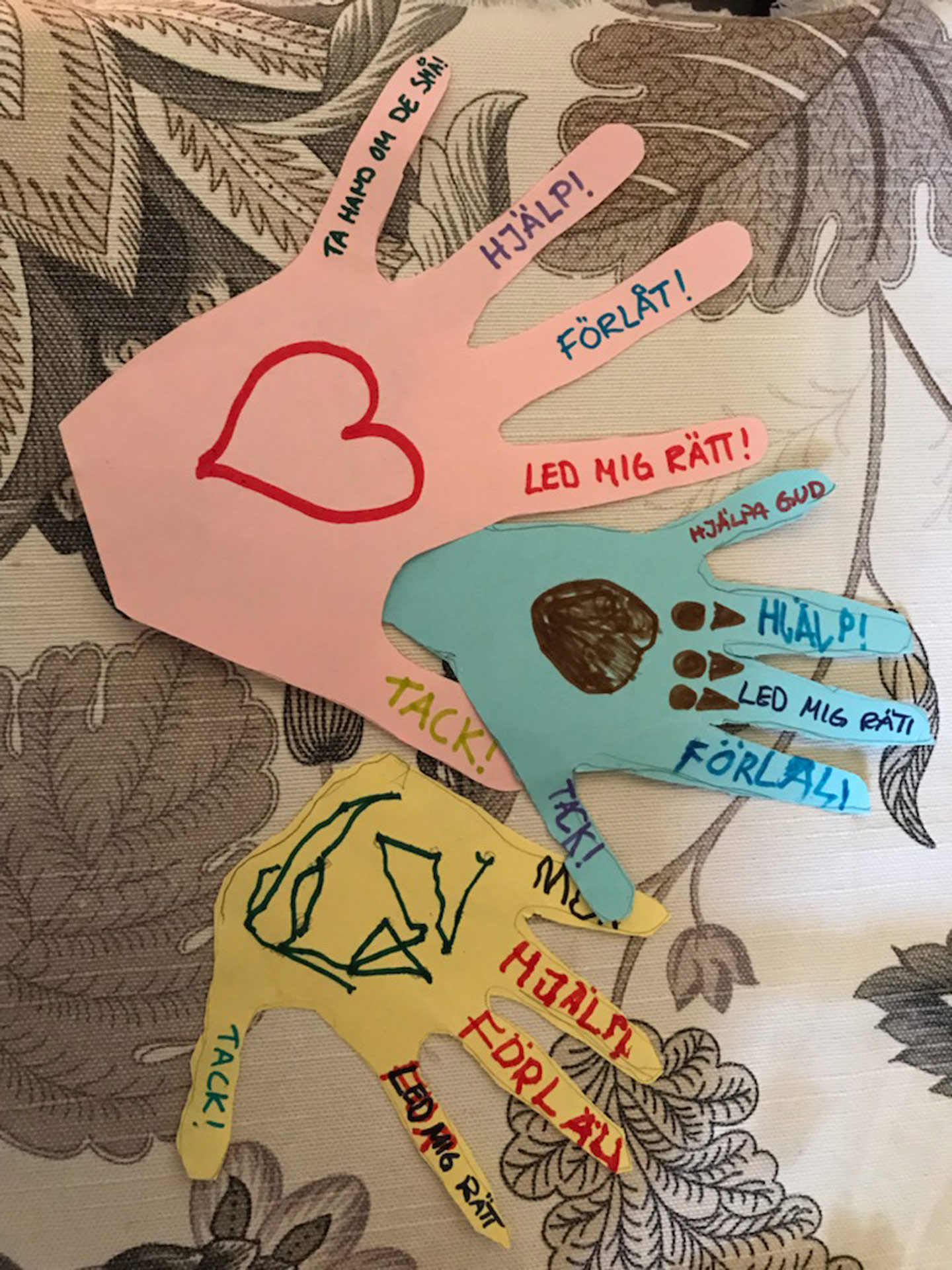 Utklippta färglgda händer med text på fingrarna.